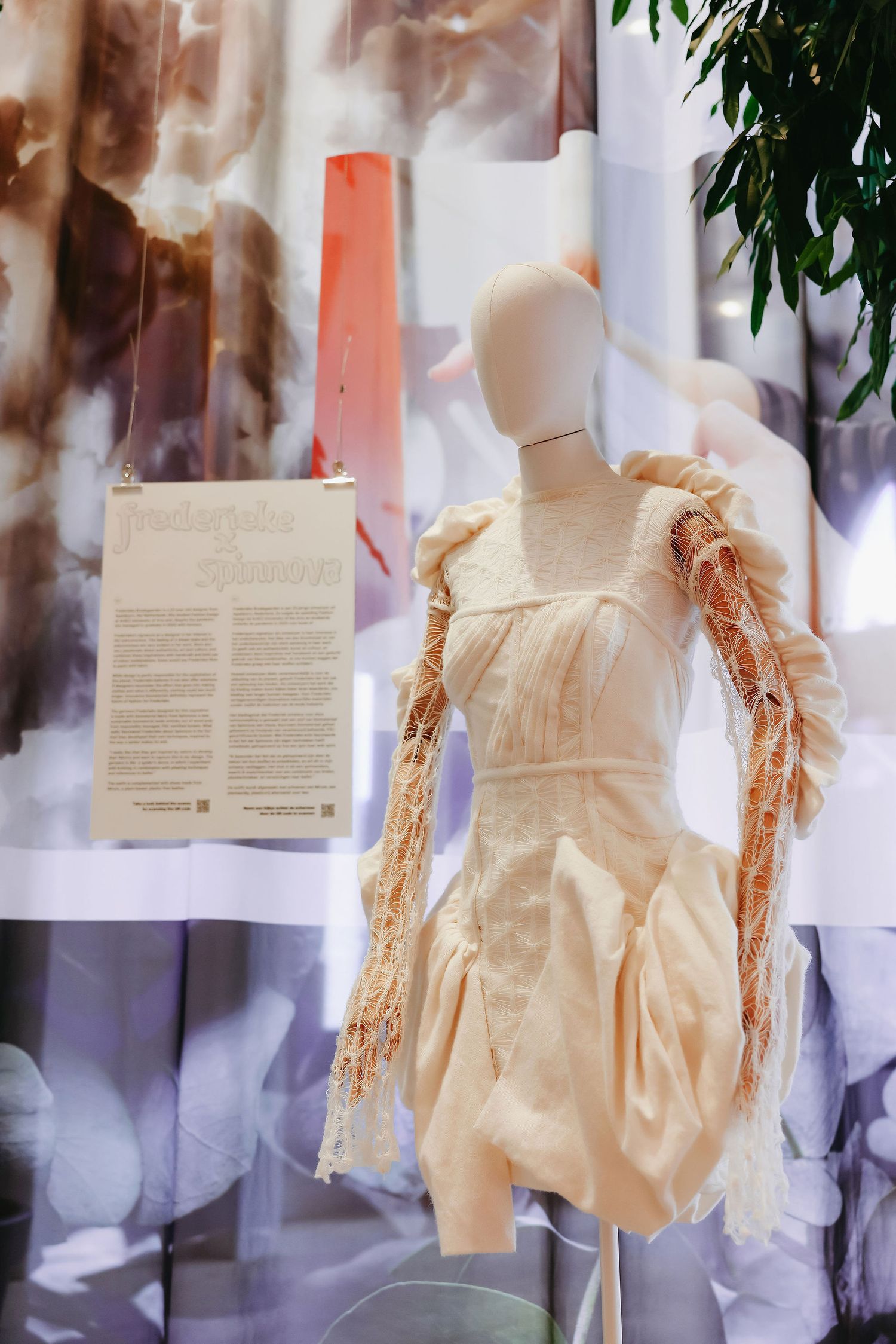 Cream-colored dress with textured sleeves on mannequin against abstract backdrop with descriptive text.