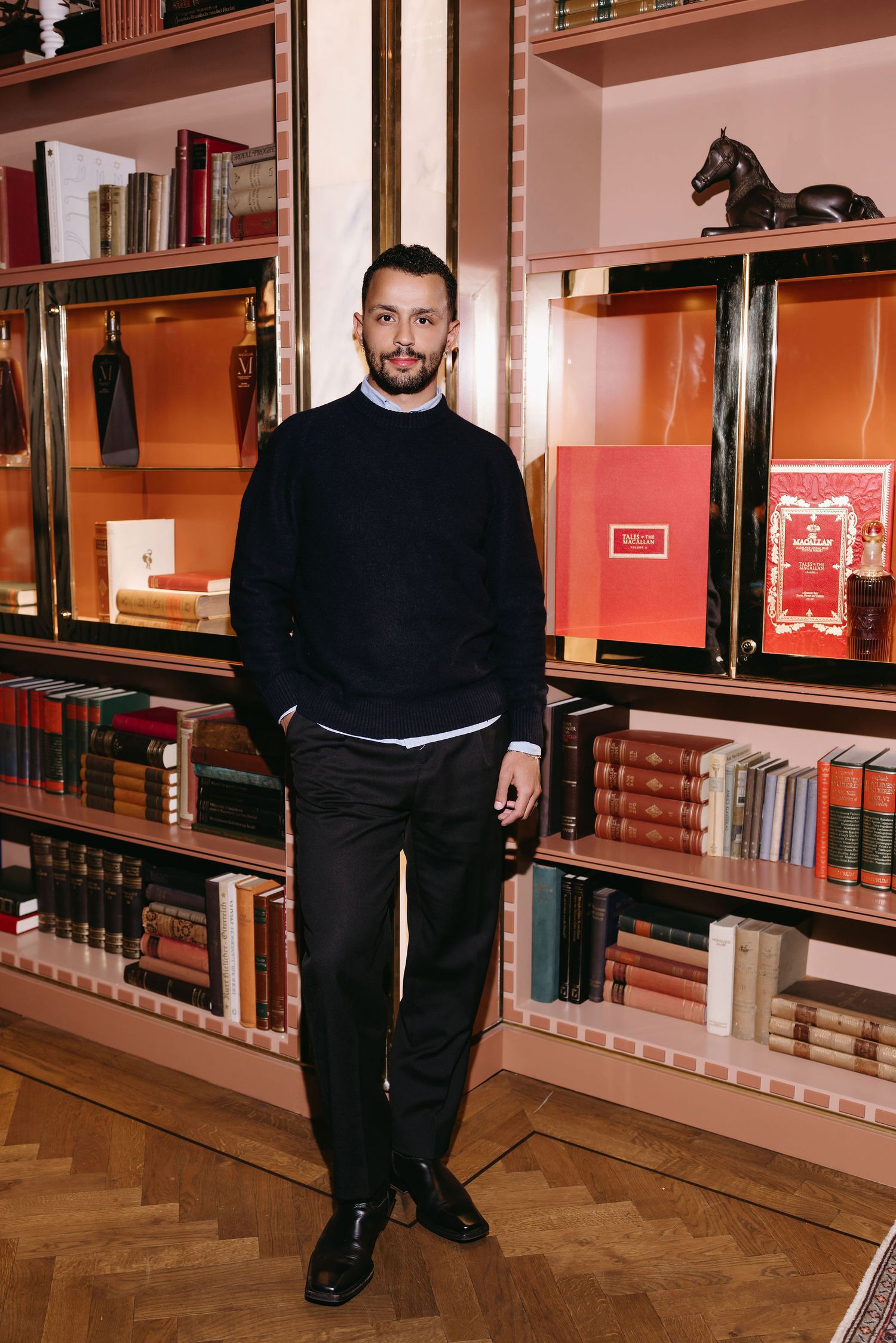 A person stands in front of built-in bookshelves with display cases in an elegant setting.