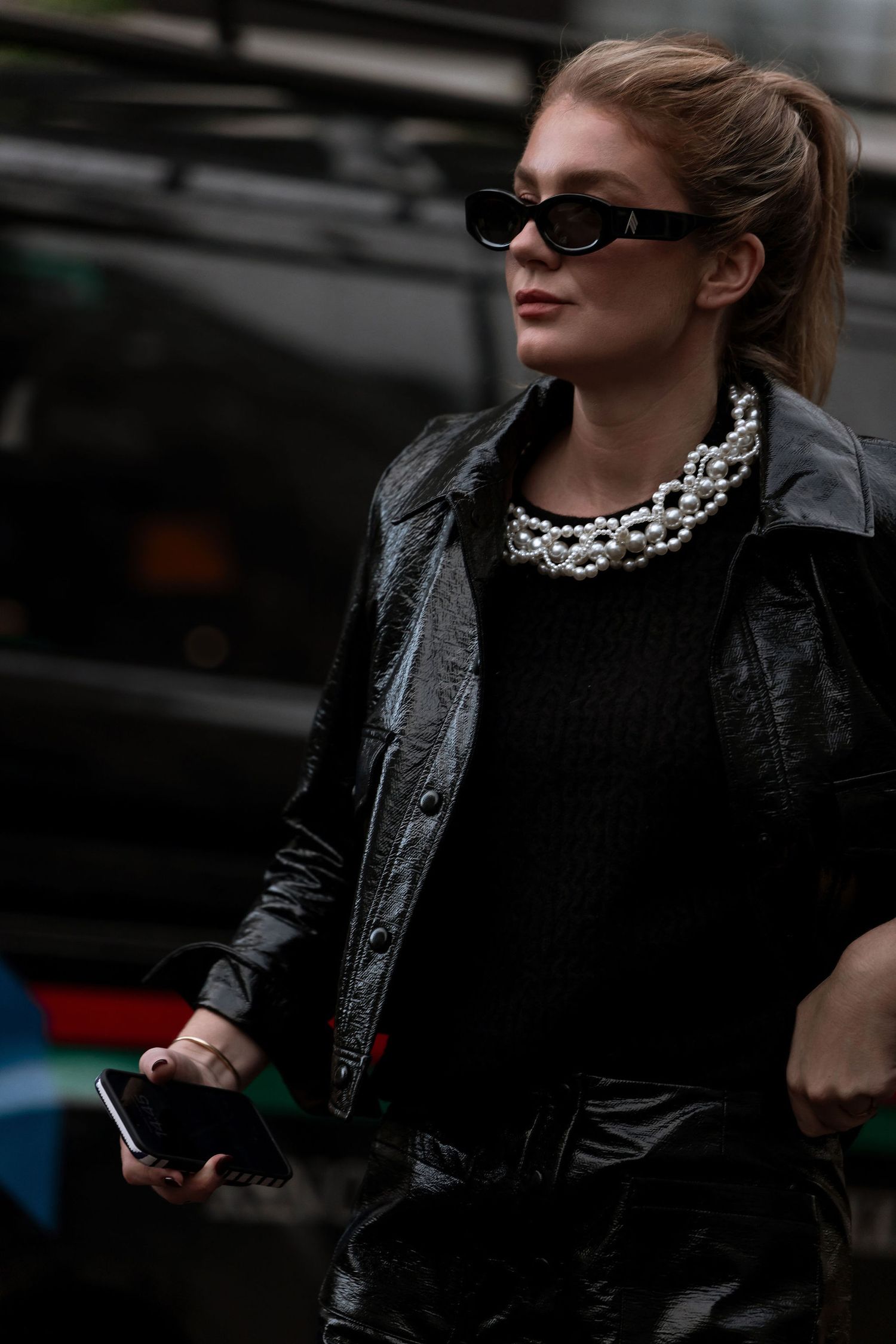 Stylish street fashion look with black leather jacket, statement necklace and slim sunglasses.