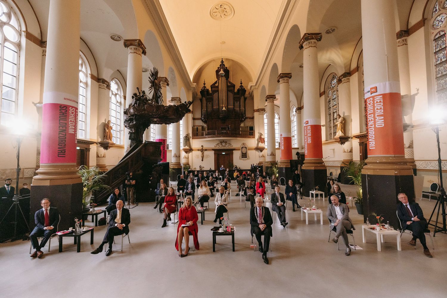 A church interior with rows of socially distanced chairs and people under vaulted ceilings.