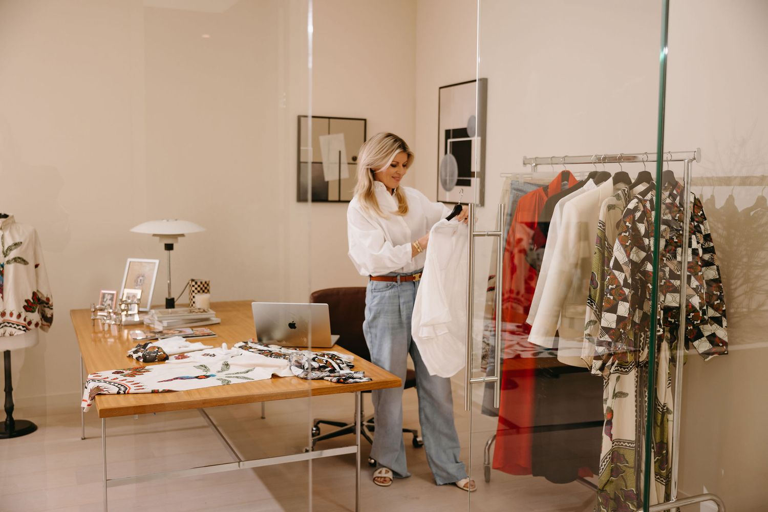 Interior of fashion boutique showing workspace with laptop, clothing racks and decor.
