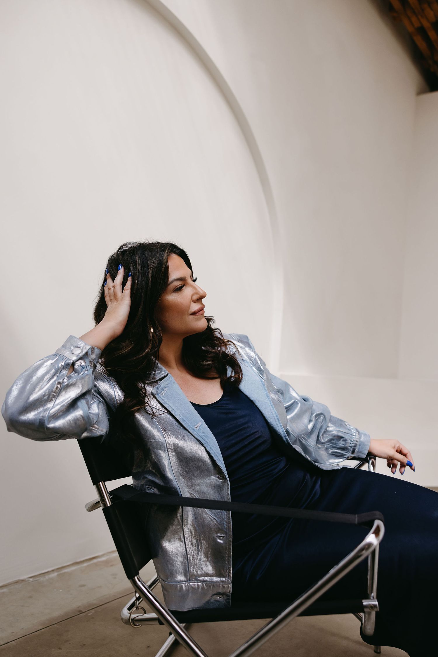 Stylish portrait of person in metallic jacket sitting in modern chair.