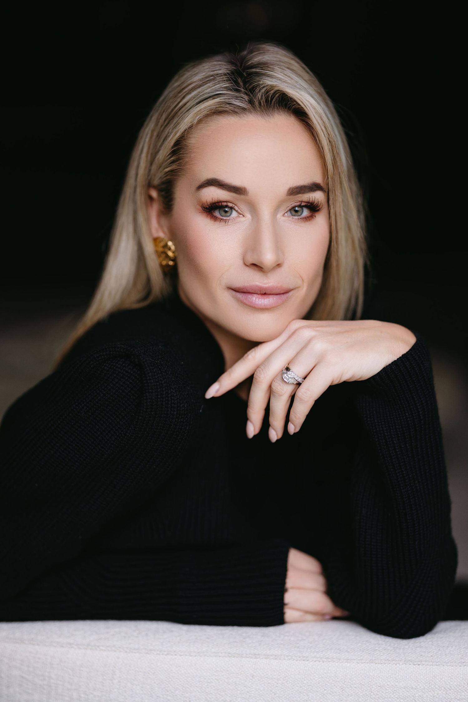 Professional headshot featuring black sweater and delicate jewelry.