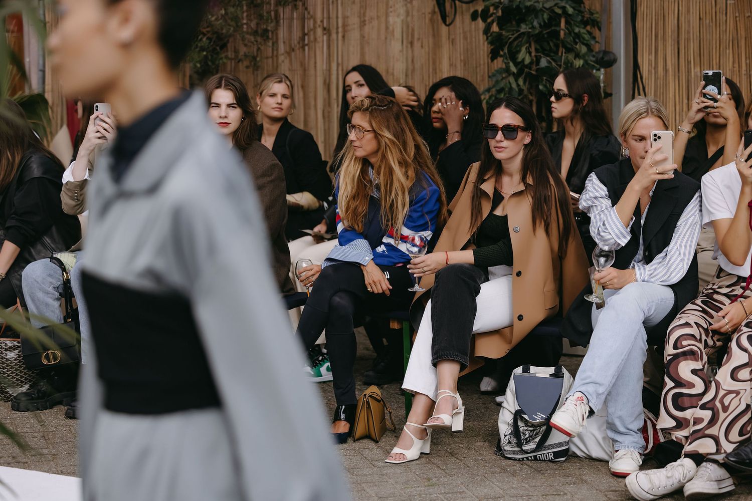 Fashion show audience seated outdoors watching runway presentation.