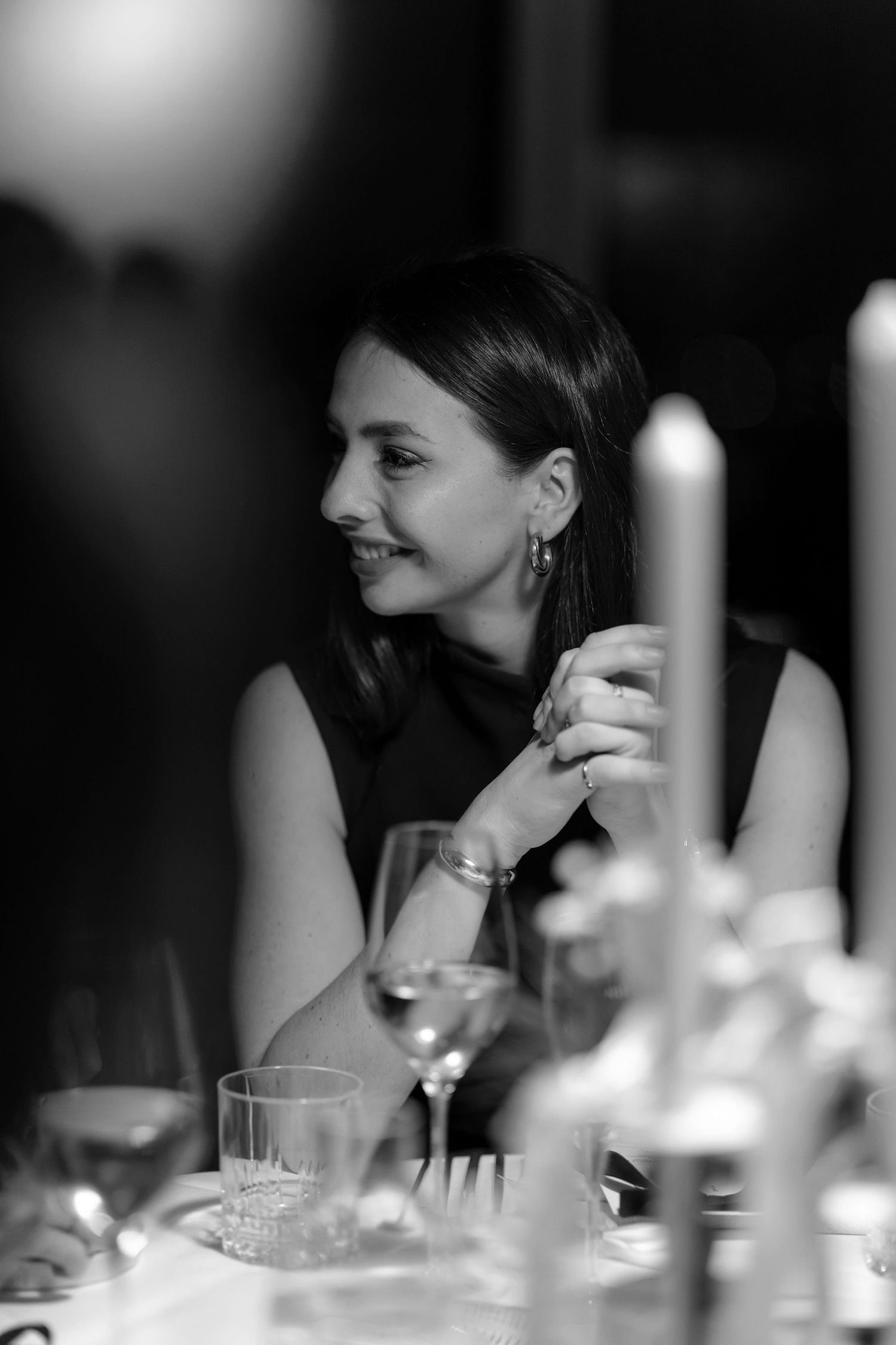 An intimate black and white portrait at a candlelit dinner table with wine glasses.