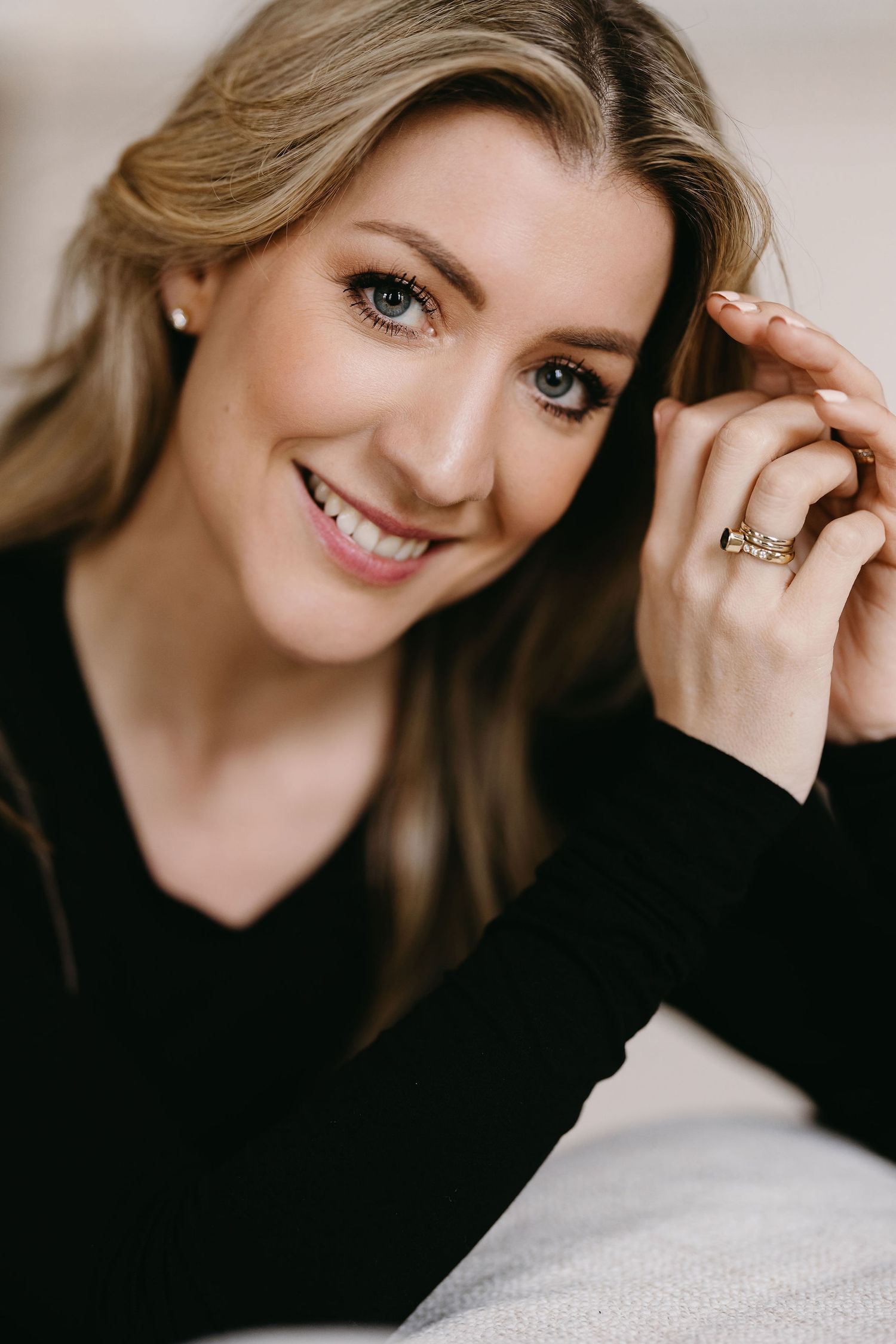 Close-up beauty portrait in black sweater with natural makeup and jewelry.