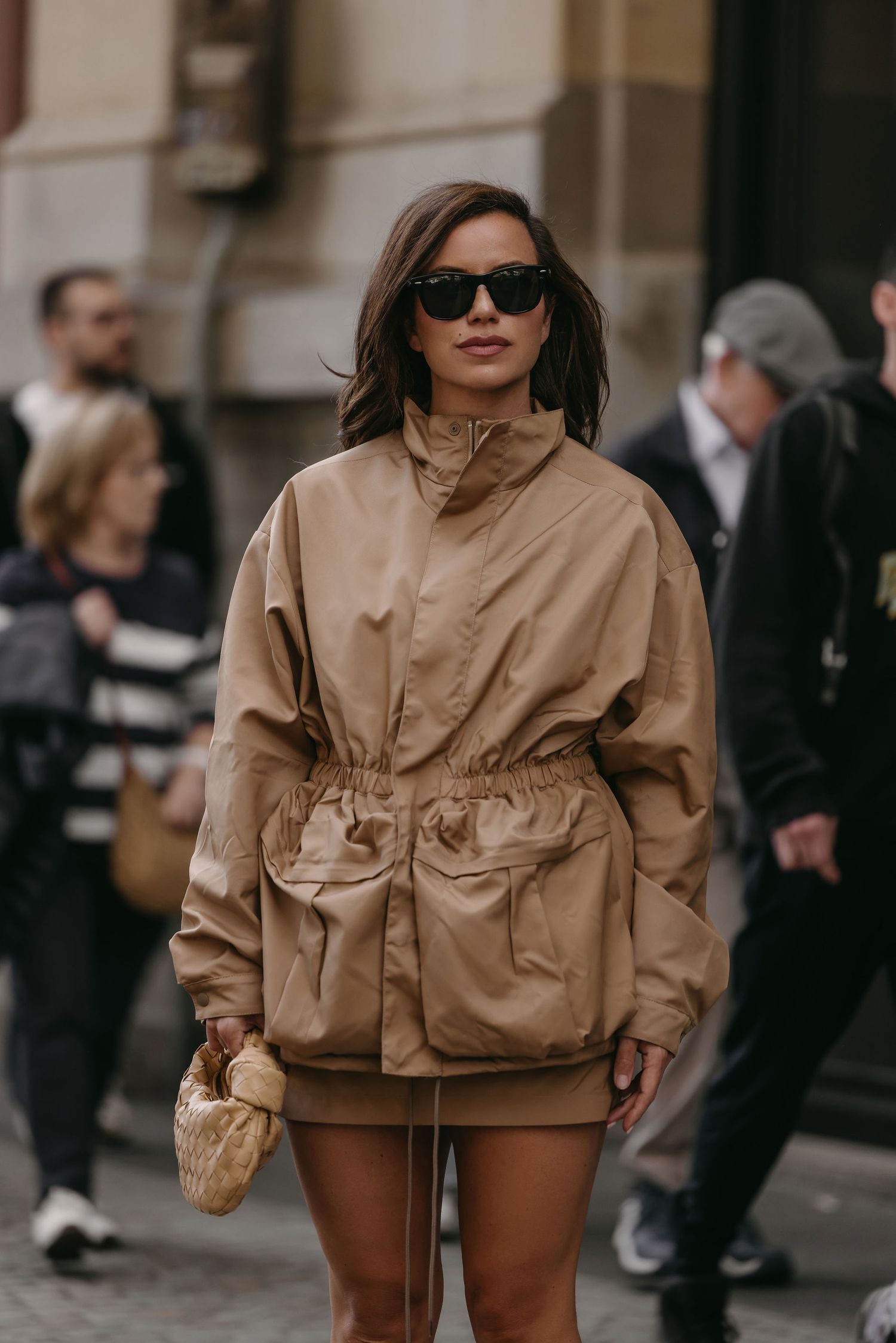 Street fashion look featuring oversized tan utility jacket and mini bag against urban background.