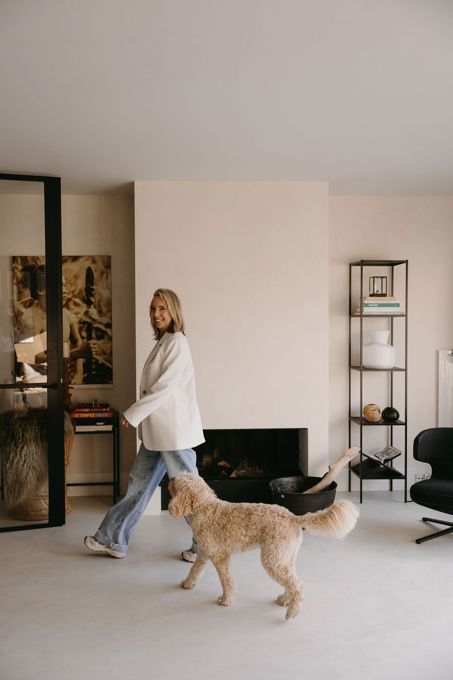 Casual home scene with white oversized shirt, jeans and golden retriever dog in modern interior.