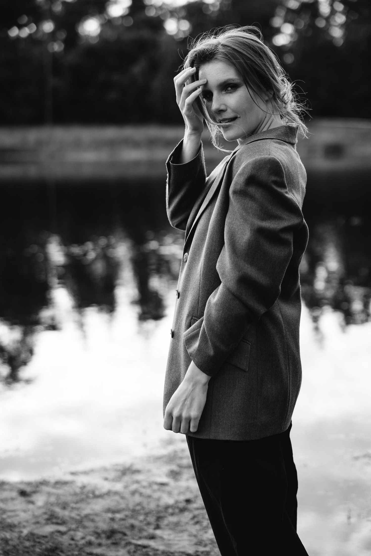 Black and white outdoor portrait with blazer against reflective water background at dusk.