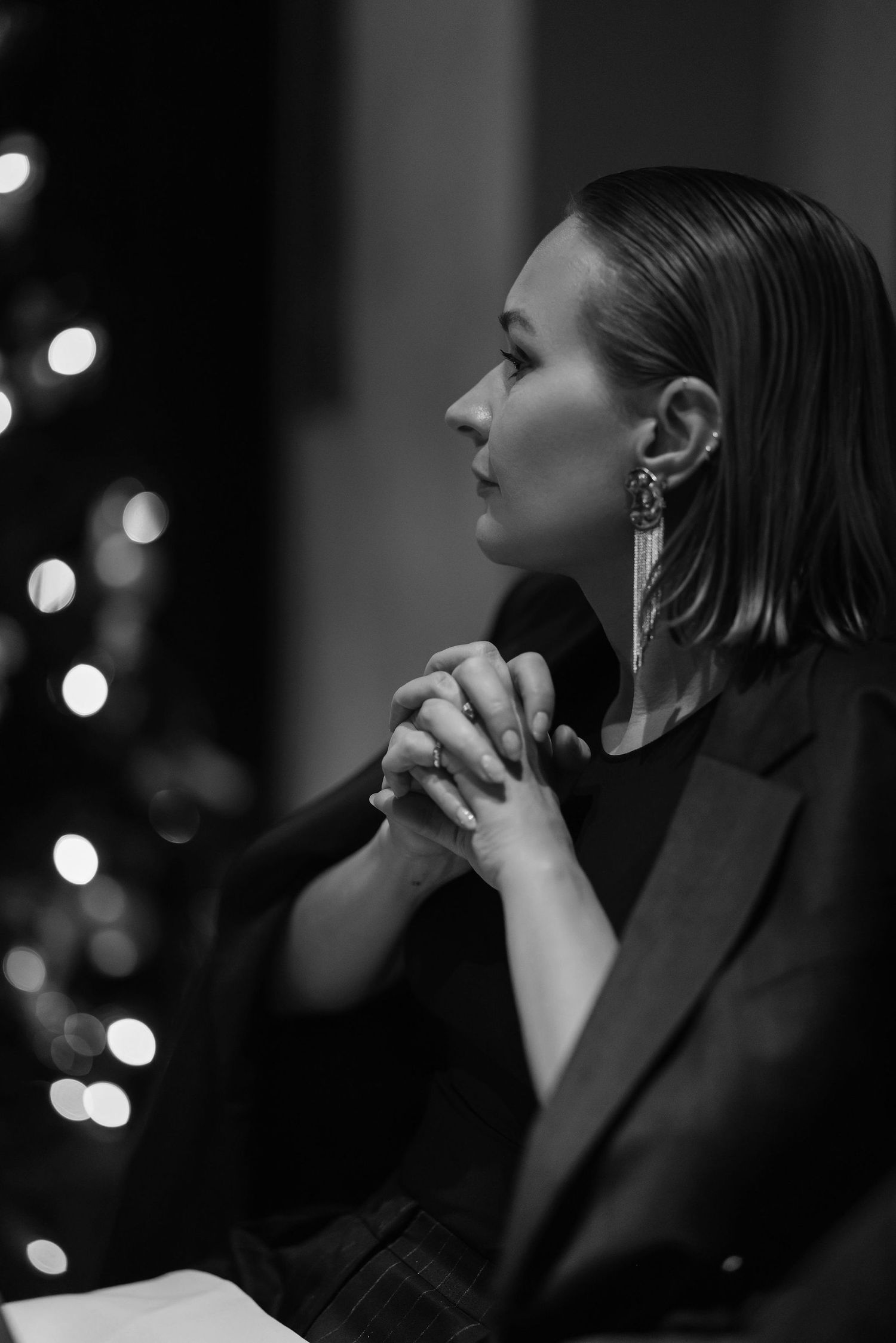 Artistic black and white profile portrait with bokeh lights in background.