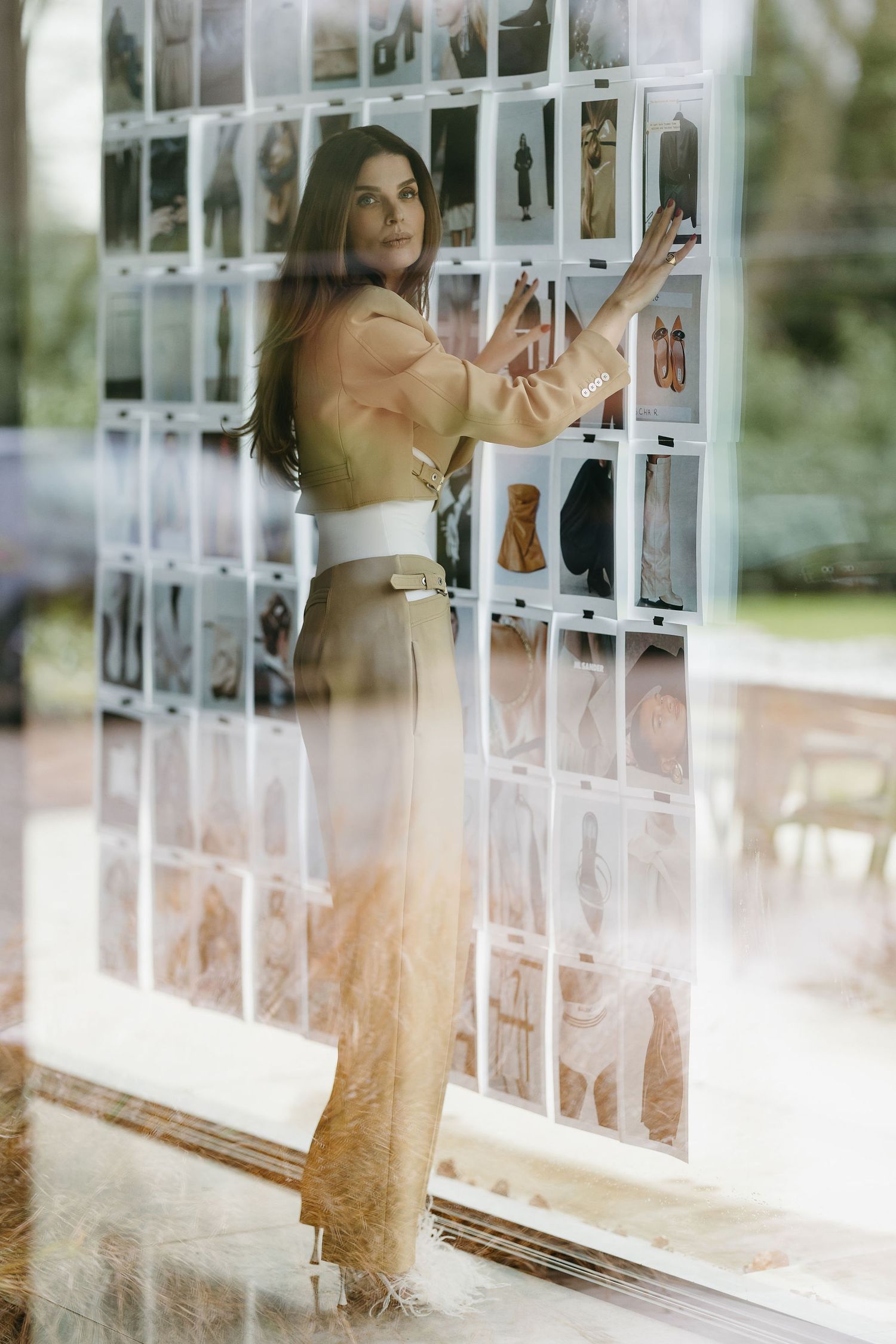 Fashion photo of a model standing next to a wall display with white panels in a light, ethereal setting.
