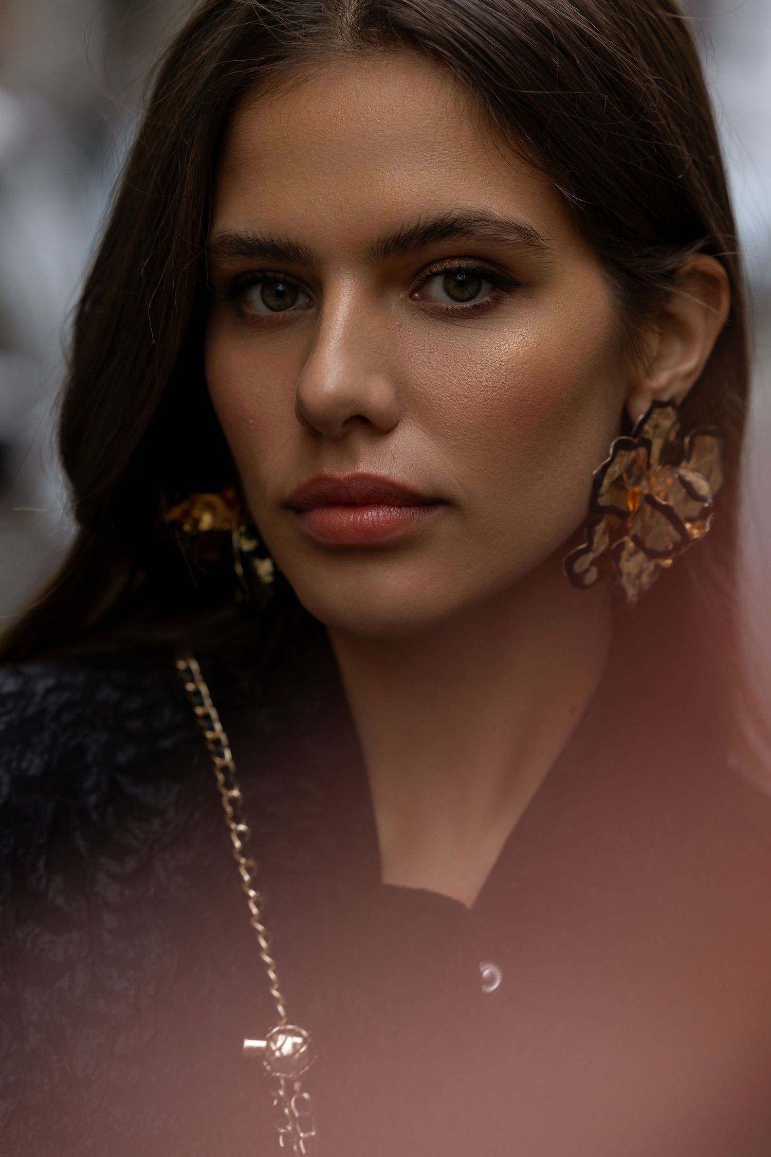 Close-up fashion portrait highlighting statement earrings and elegant makeup.