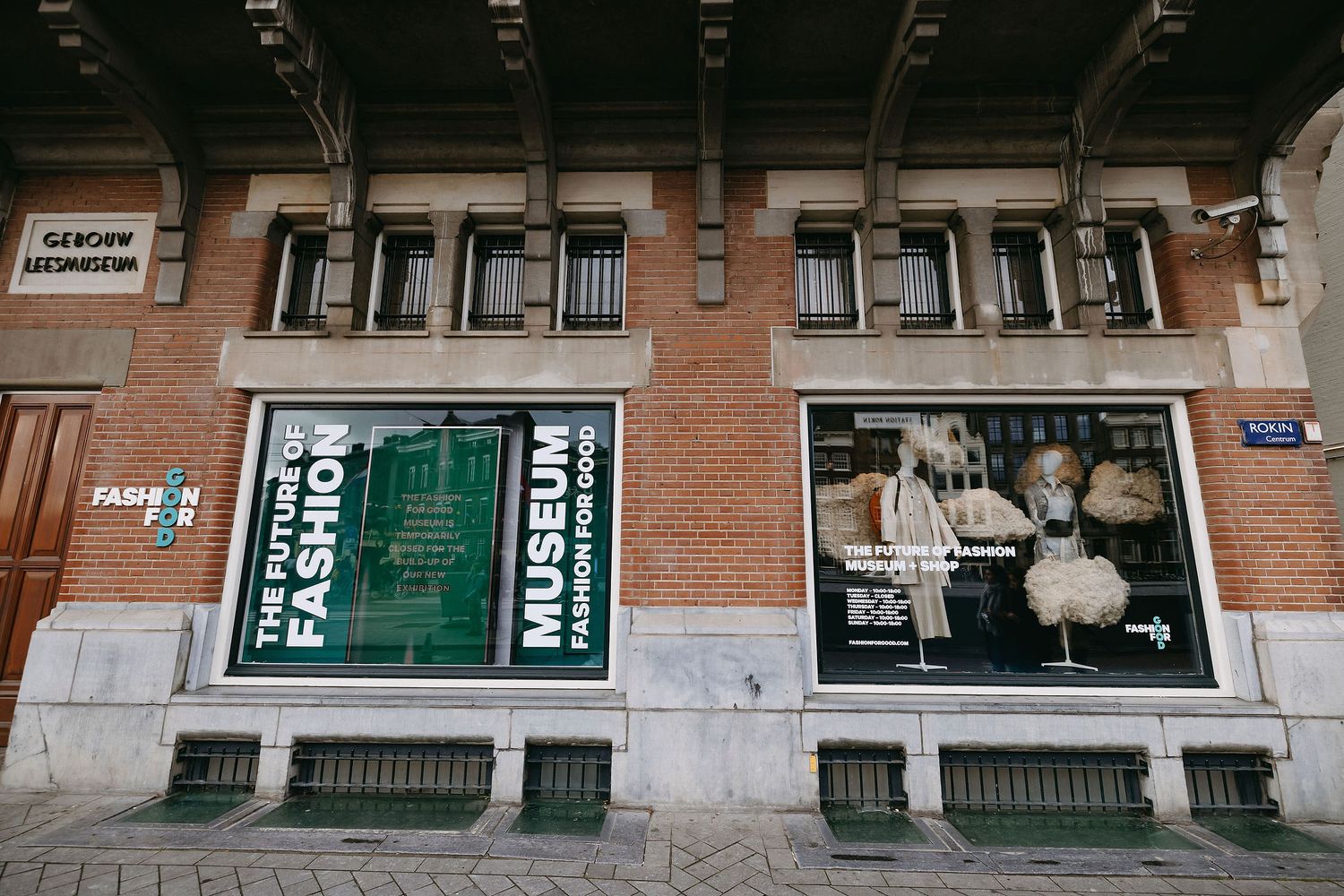 Exterior view of a brick building with large display windows and green banners.