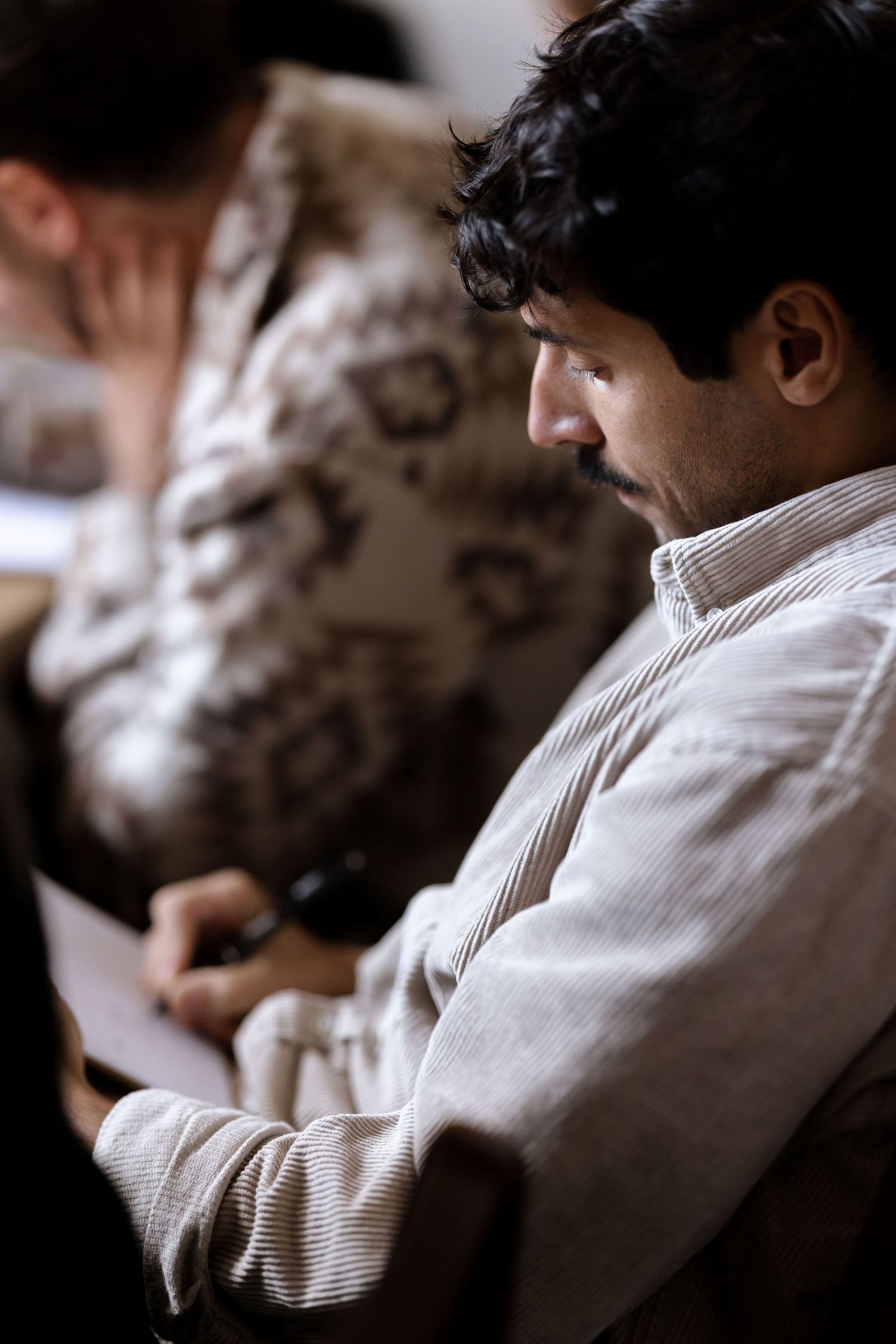 Person in white shirt sitting in contemplative side profile.
