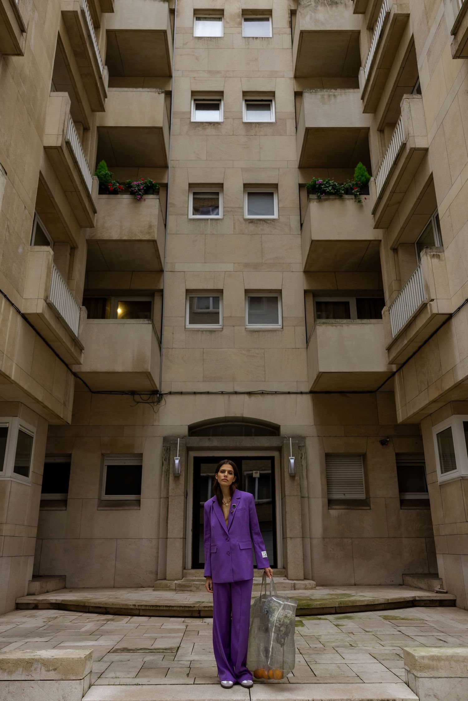 Striking architectural photo of person in bright purple suit against brutalist concrete building.