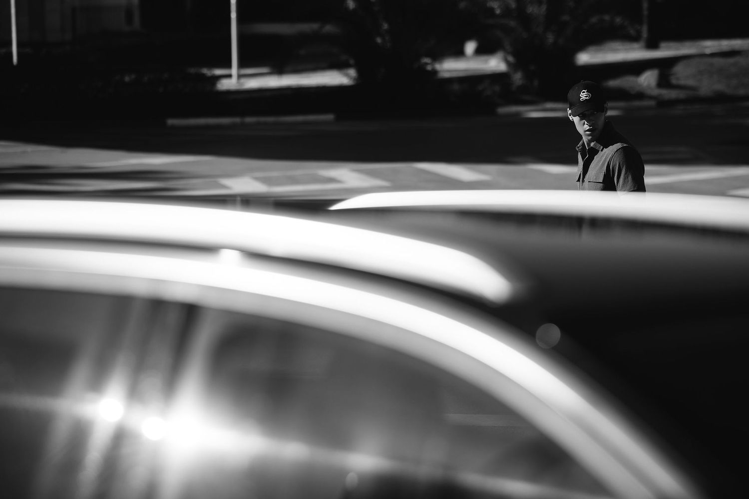 Black and white artistic photo showing reflections on a car surface with blurred background.