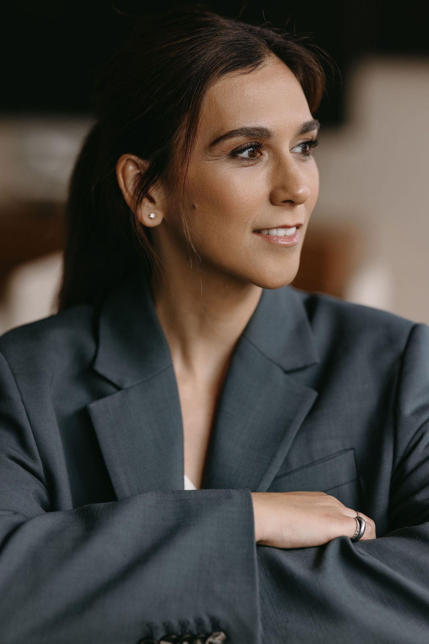 Professional headshot of someone wearing a gray blazer with warm lighting and subtle smile.