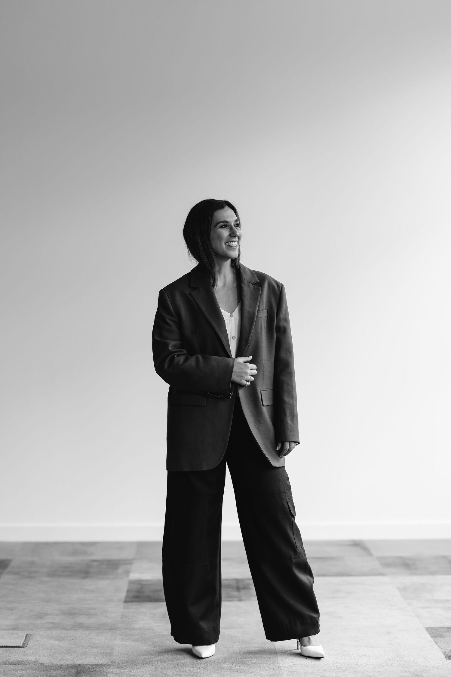 Minimalist black and white portrait showing person in oversized blazer and wide-leg pants.
