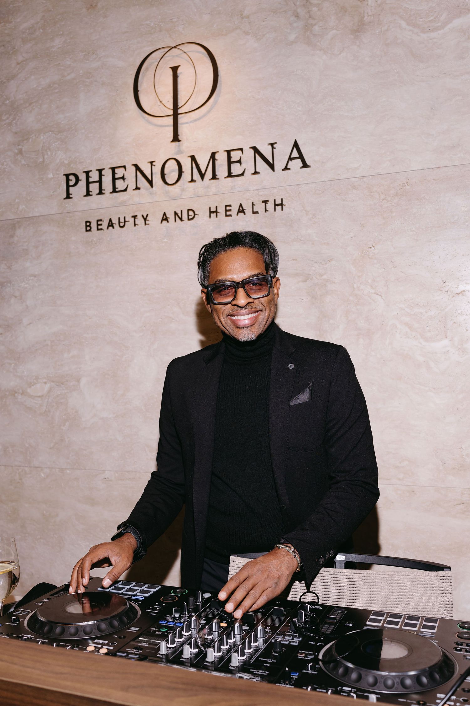 DJ performing at Phenomena Beauty and Health event with professional mixing equipment.