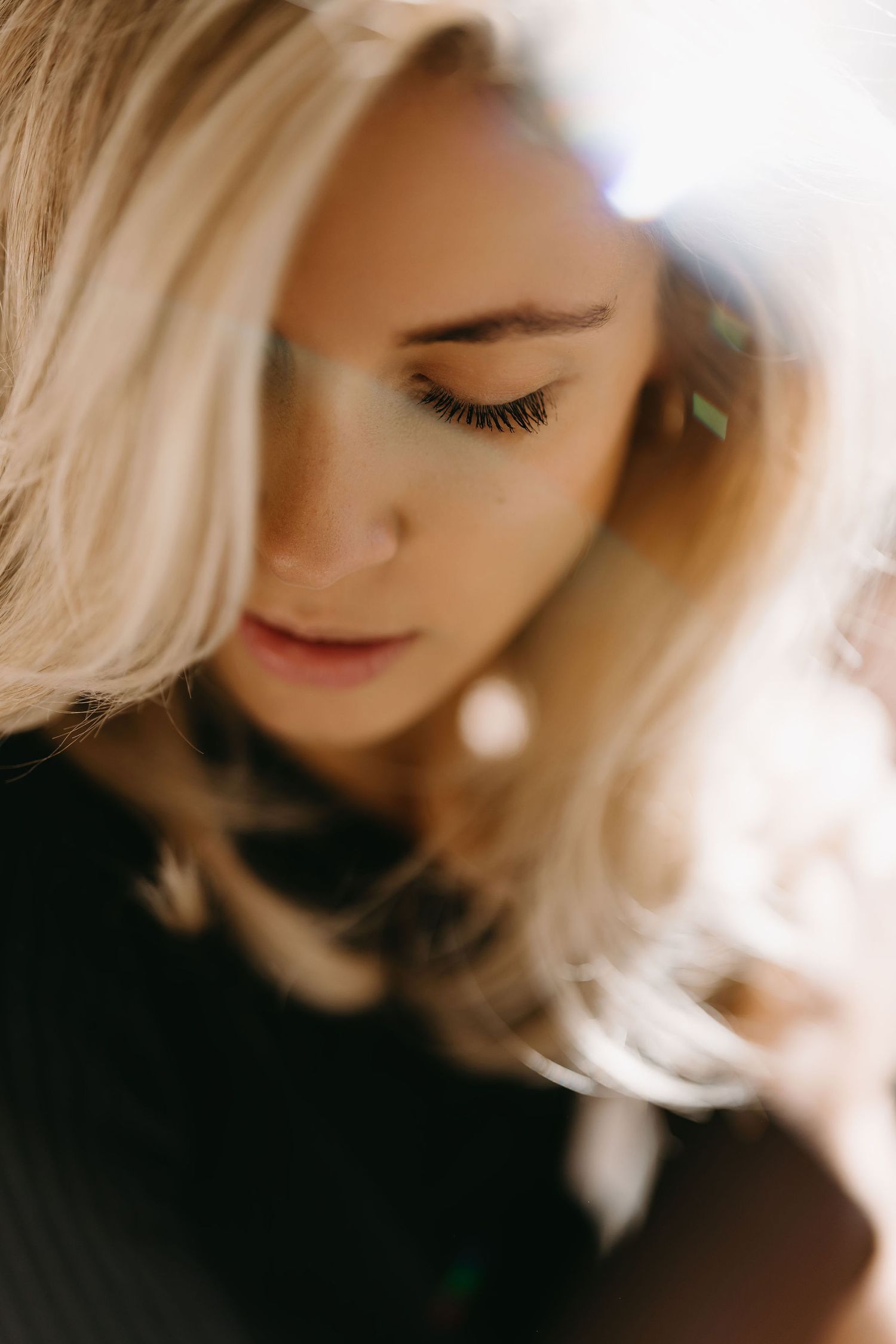 Close-up artistic portrait with soft lighting and blonde hair in focus.