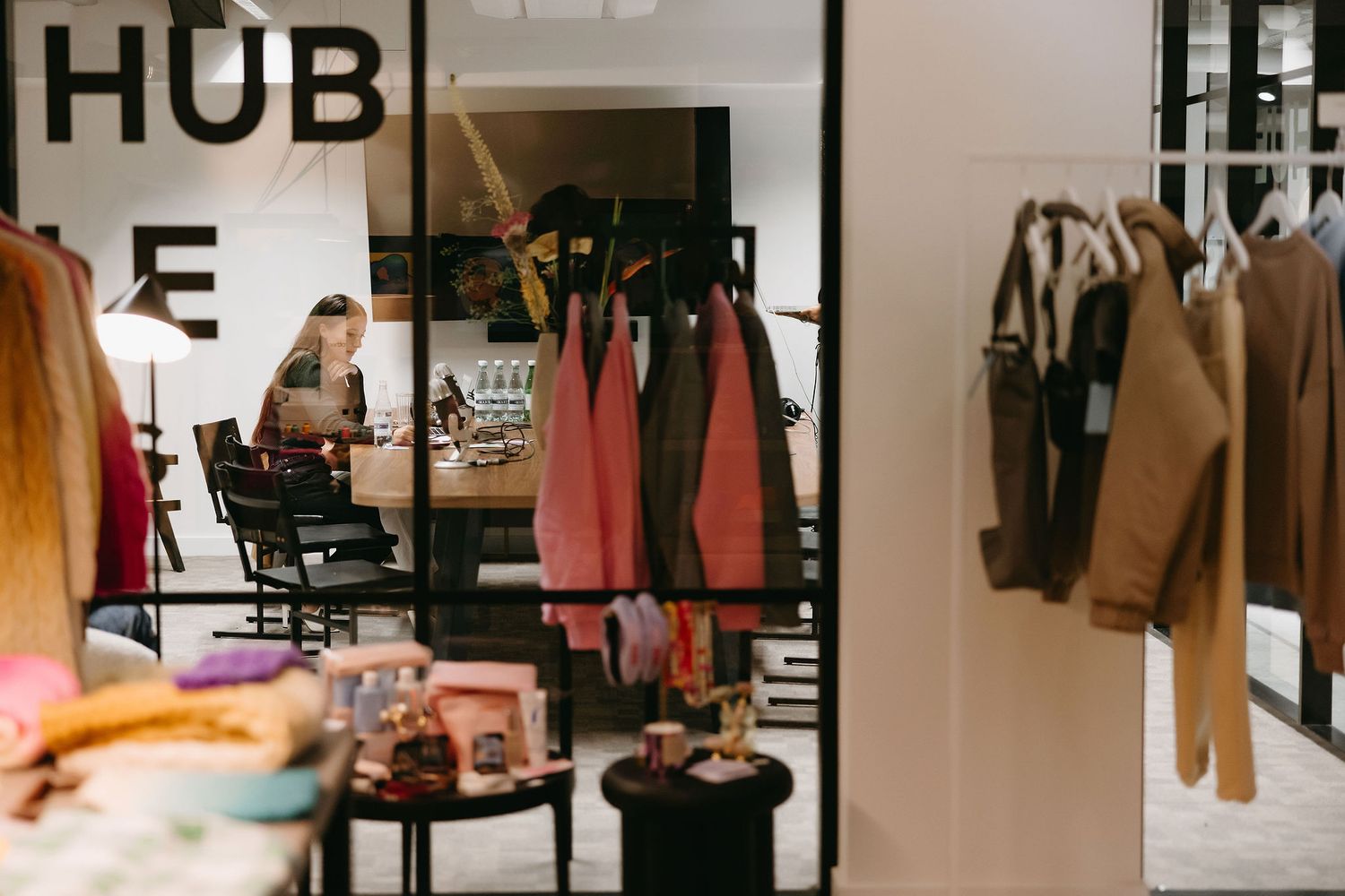 Interior of clothing retail store showing racks of coats and fashion items.