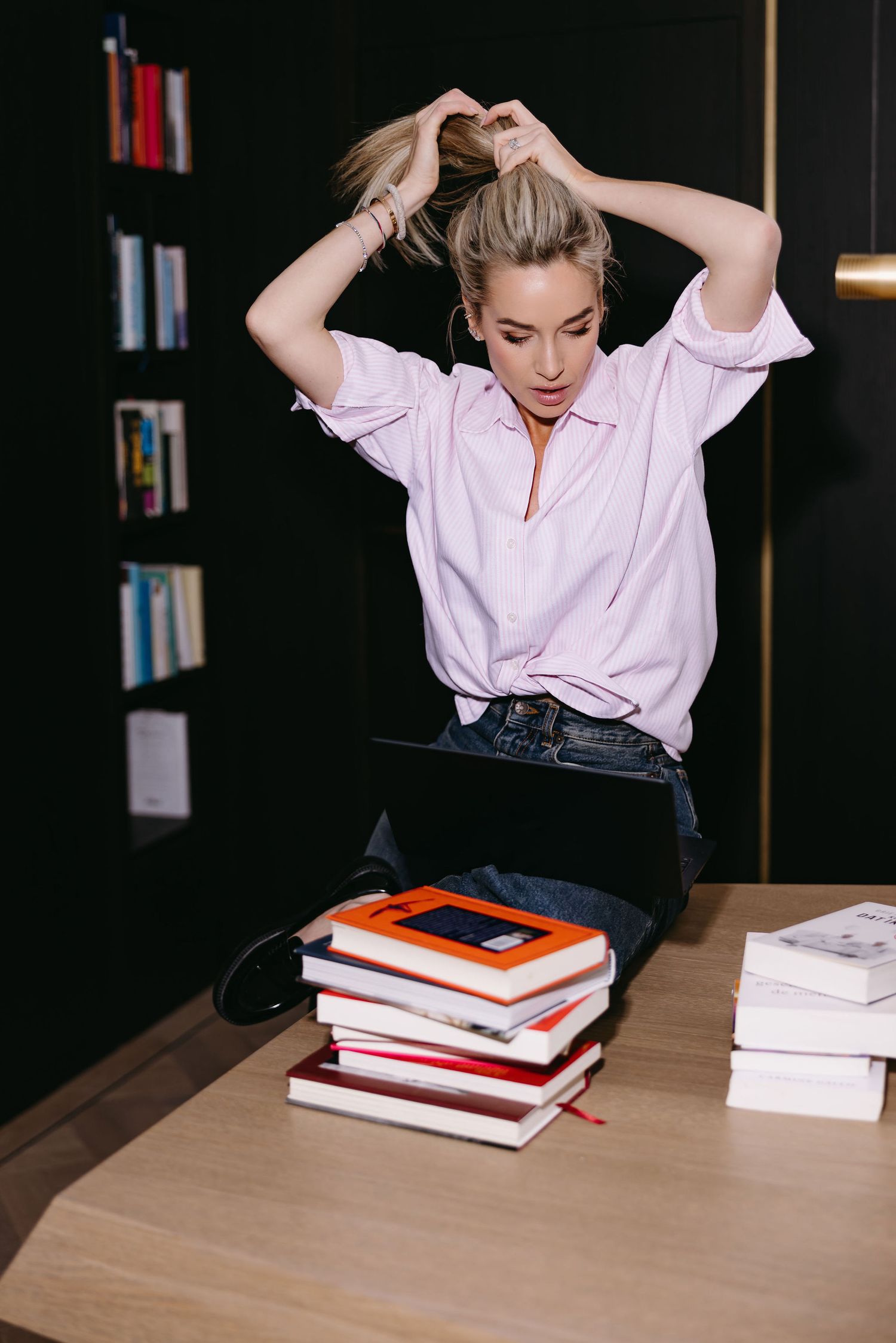 Casual study scene with pink shirt and stack of books on wooden desk.