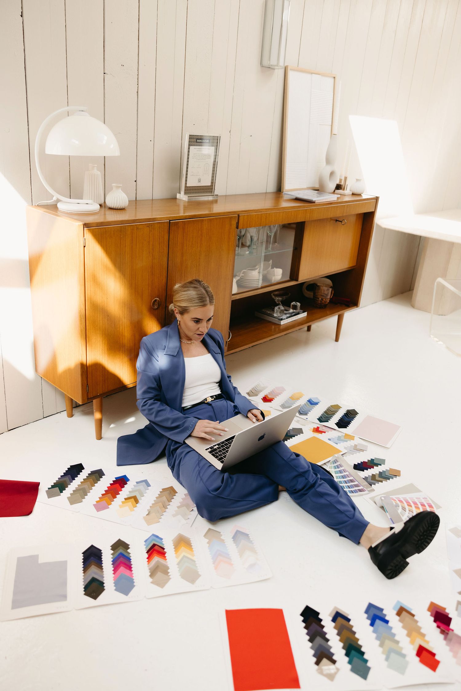 Overhead view of product samples and laptop workspace with colorful sock designs laid out on white floor.