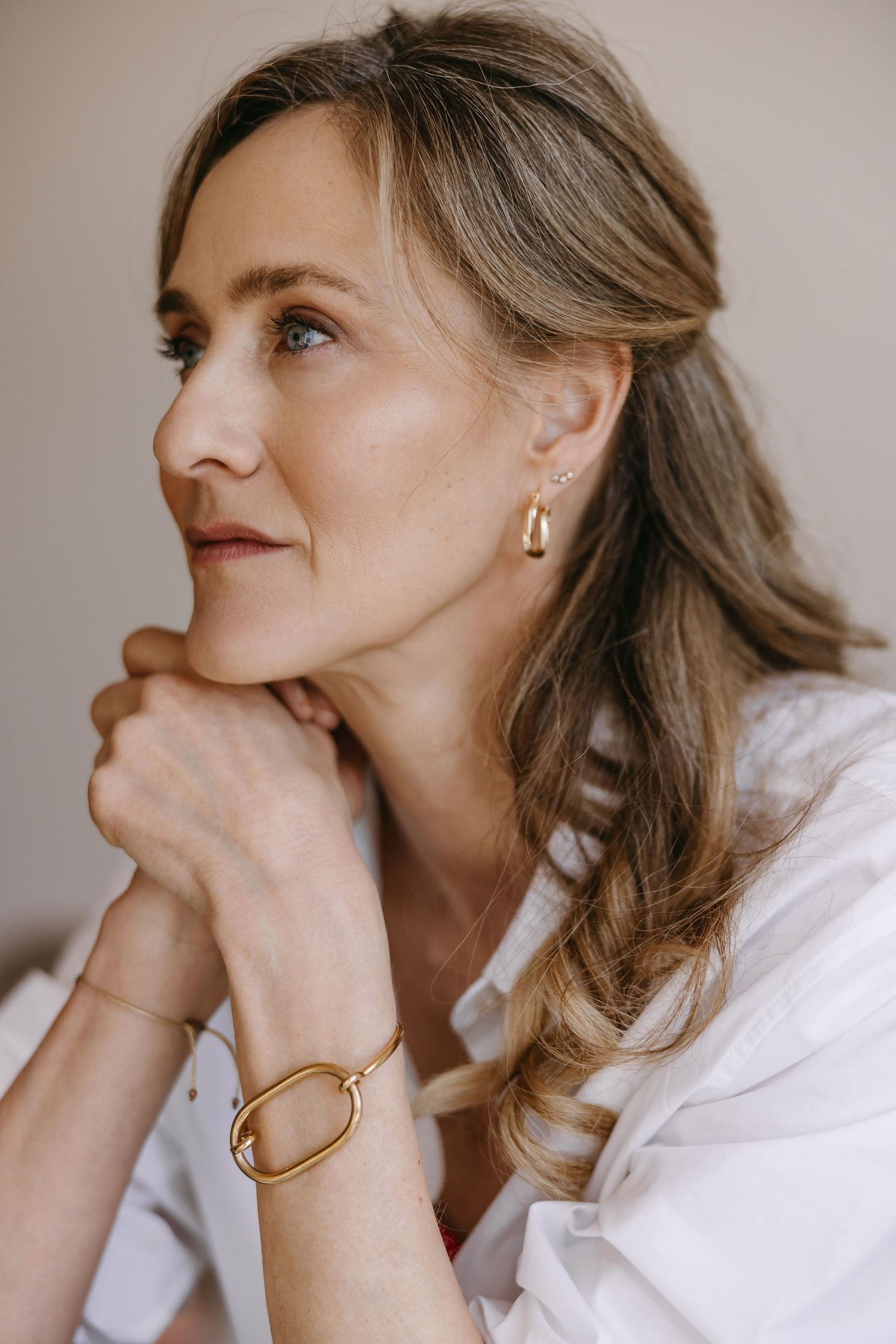 Elegant portrait with gold jewelry and classic white button-down shirt.