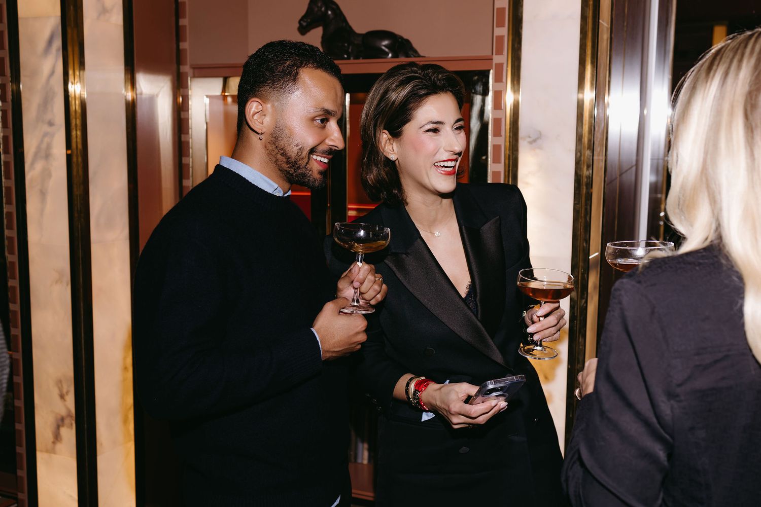 People enjoying drinks and conversation in an upscale bar setting.