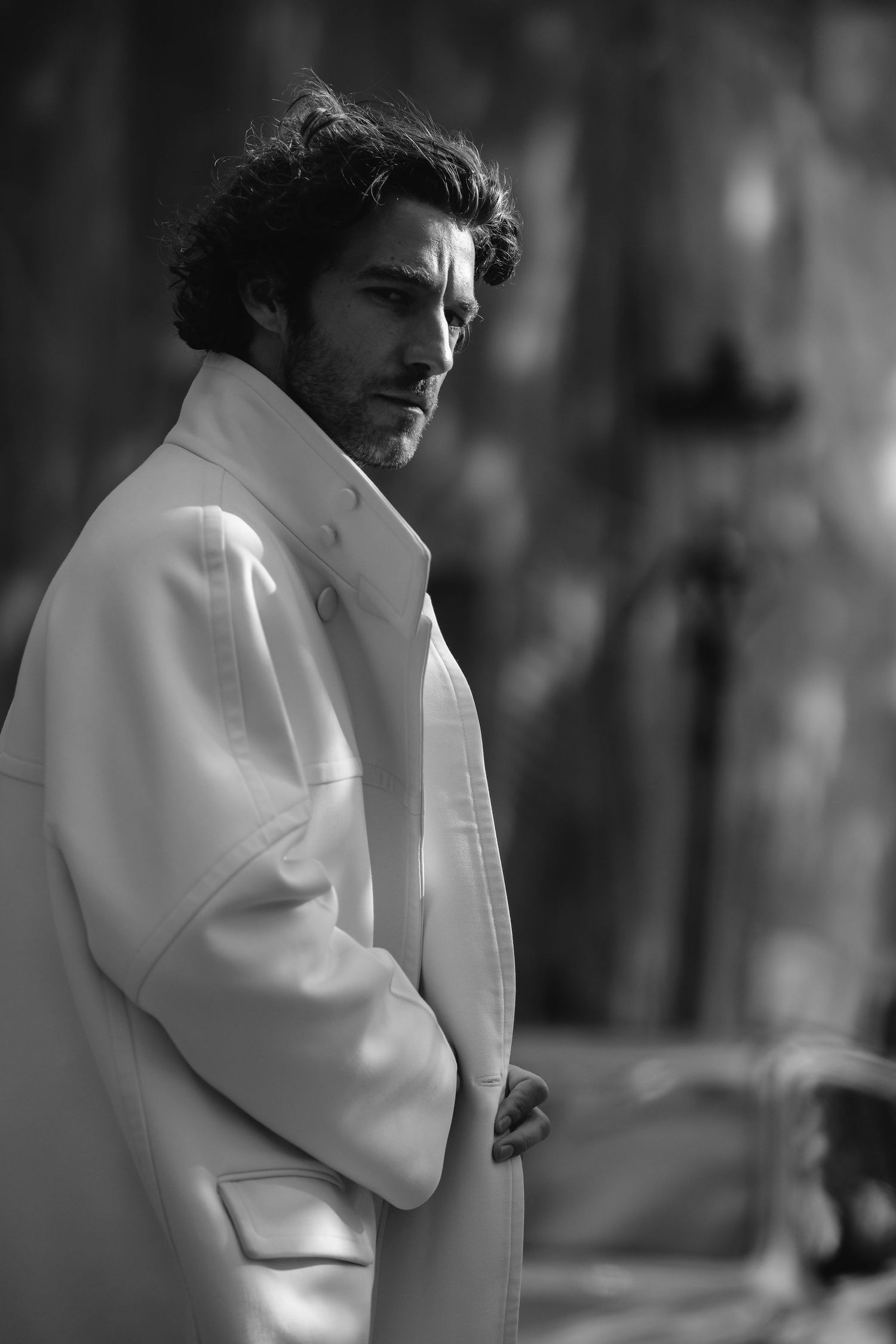 Dramatic black and white portrait featuring white oversized coat with moody lighting.
