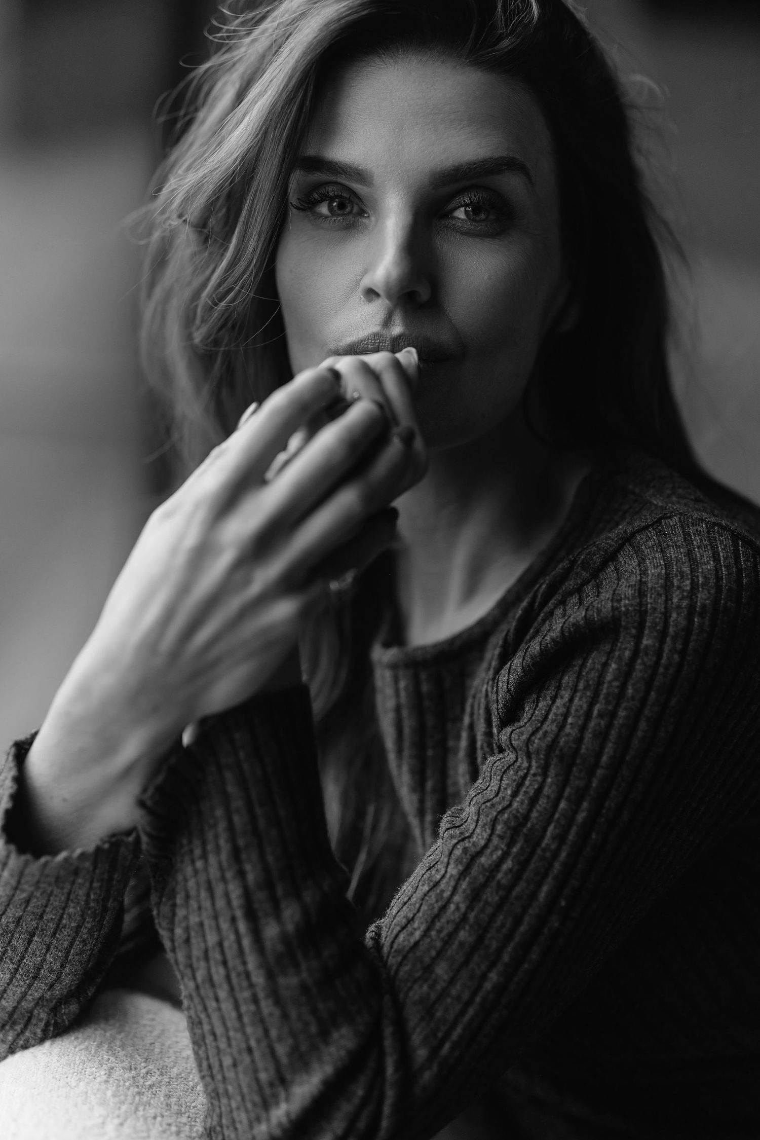 Dramatic black and white portrait with knit sweater and contemplative pose.