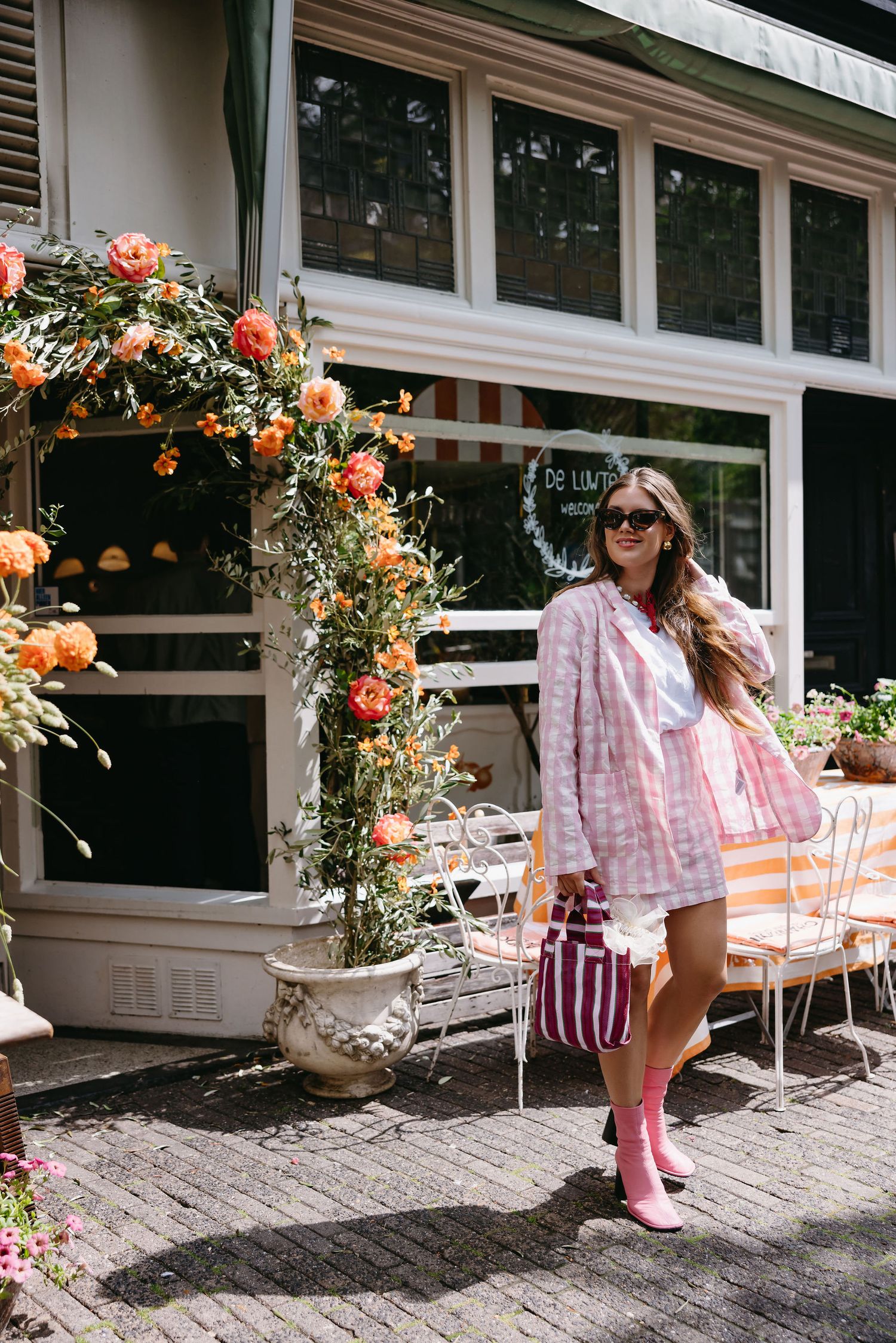 Storefront decorated with climbing orange and pink roses and outdoor seating.