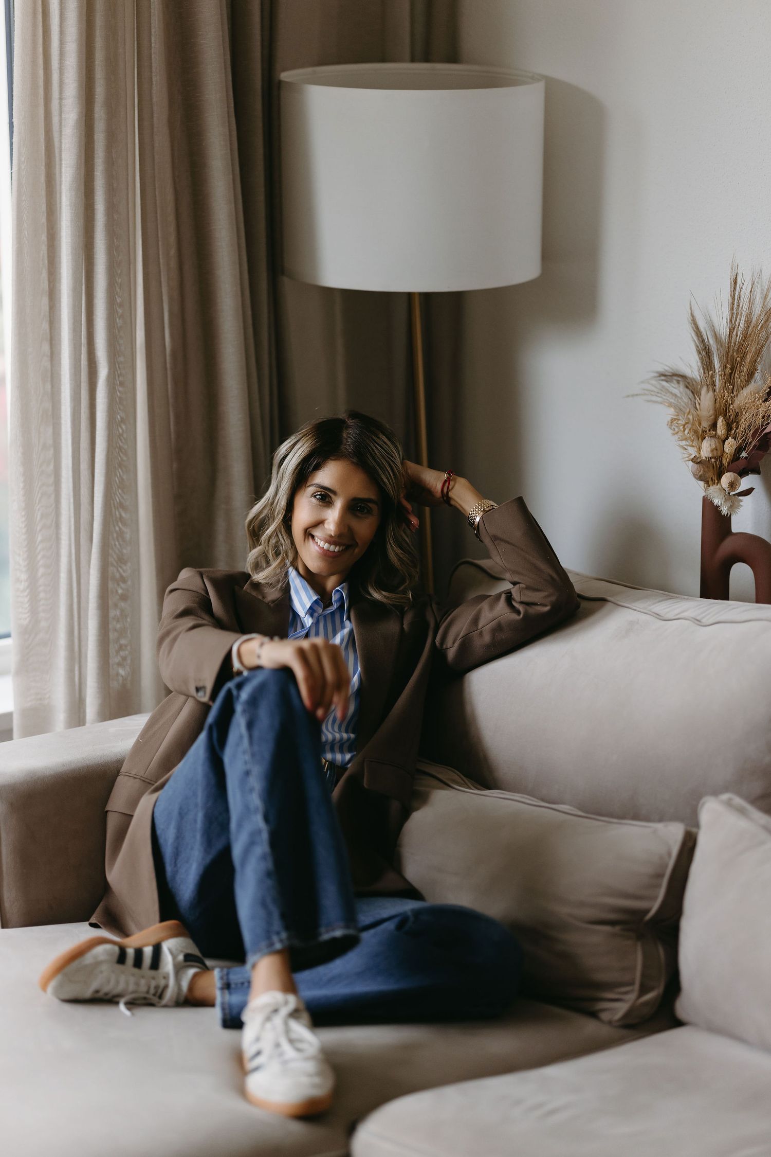 Lifestyle portrait of person relaxing on beige couch near window with modern decor.