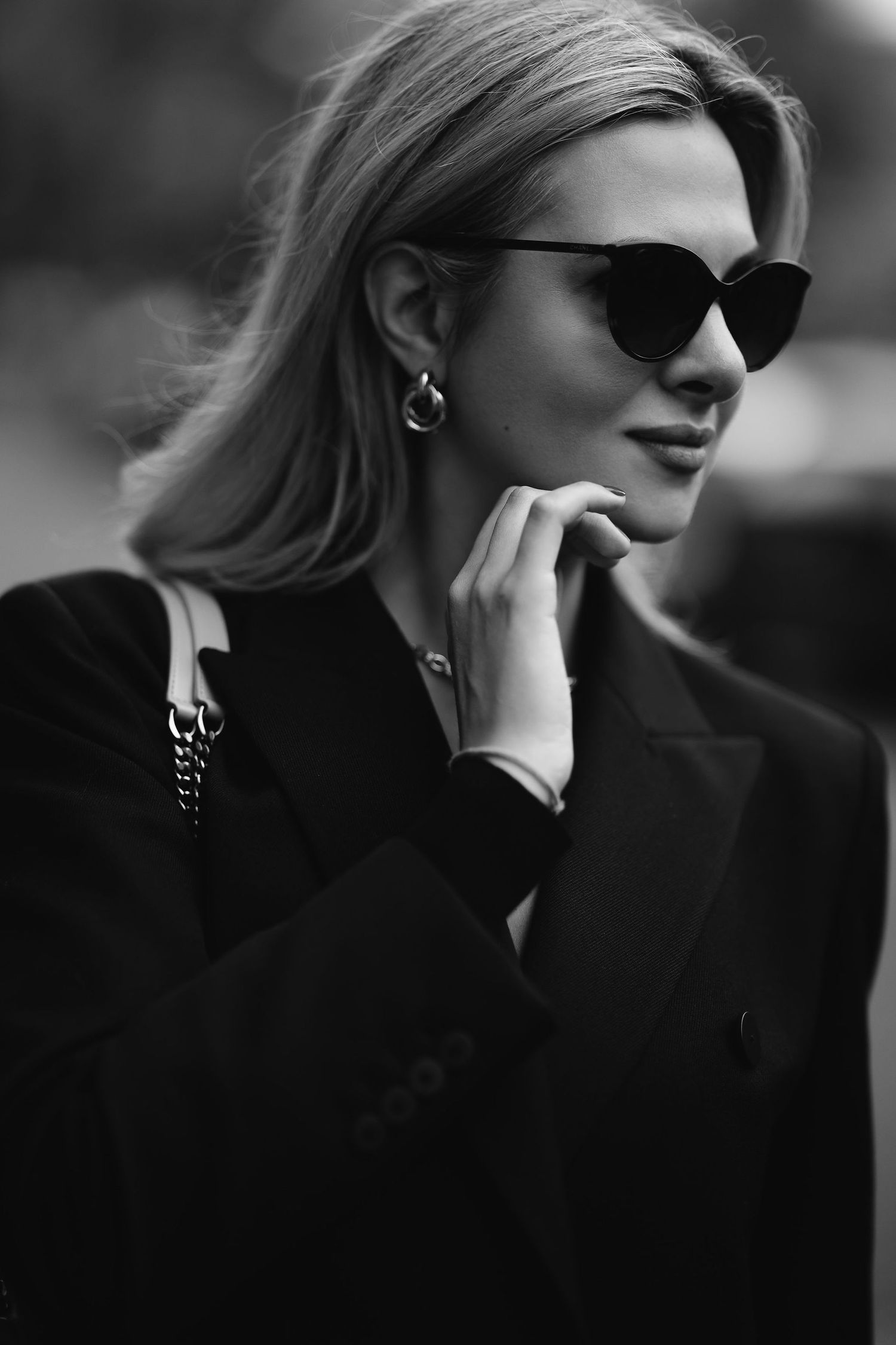 Elegant black and white fashion portrait featuring sunglasses and classic coat.