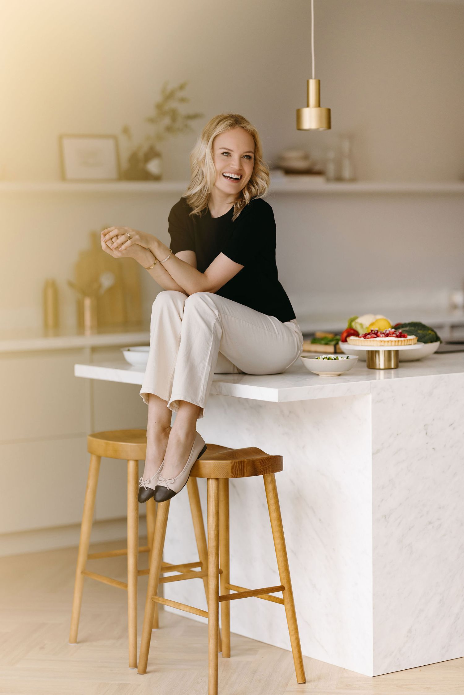 Bright lifestyle photo in modern kitchen with wooden barstools and pendant lighting.