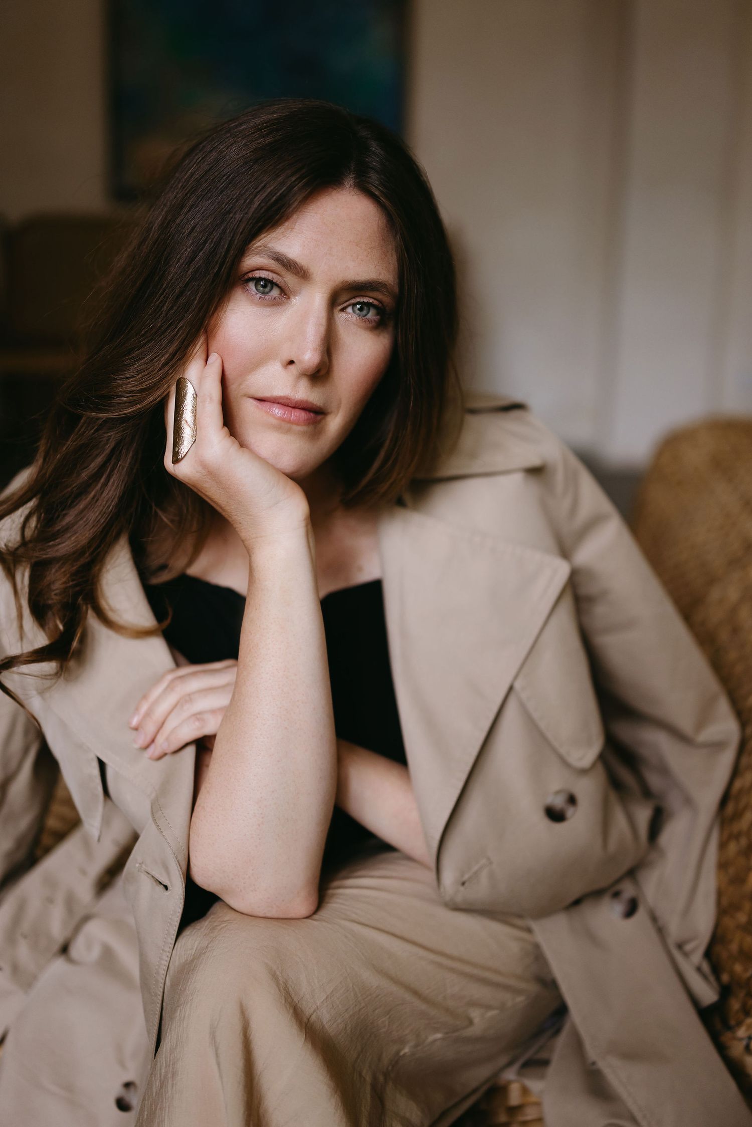 Professional fashion portrait featuring a beige trench coat against a neutral background.