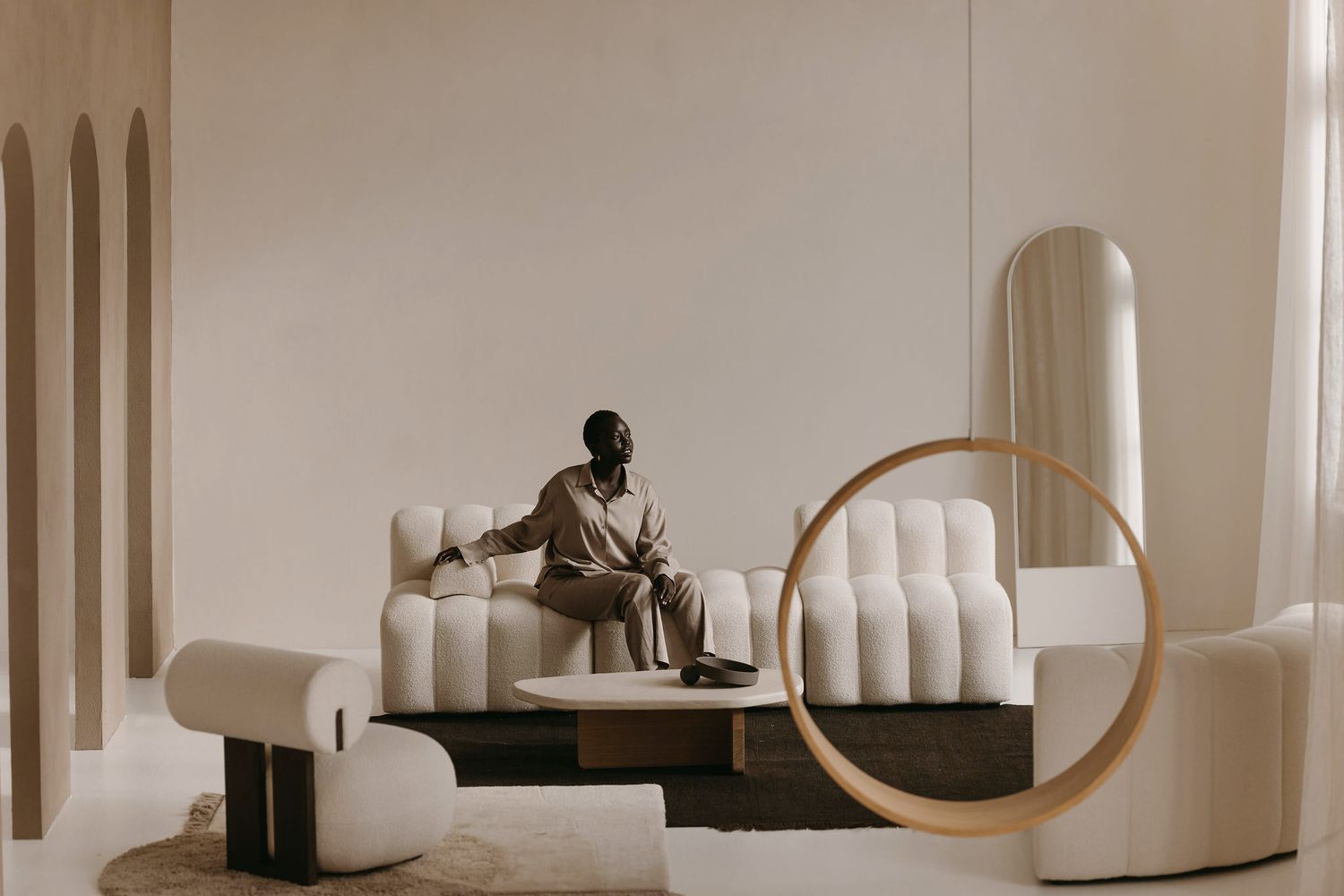 Contemporary white furniture installation with sculptural seating and circular mirror.