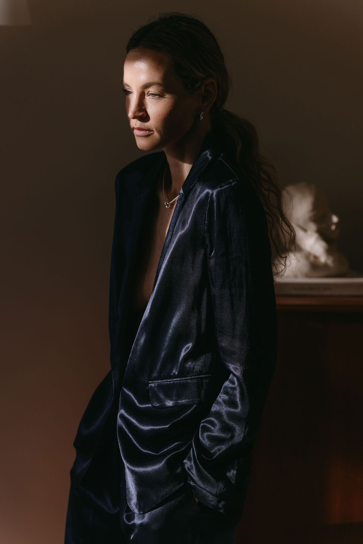 Moody portrait of a model in dark satin jacket with dramatic side lighting.