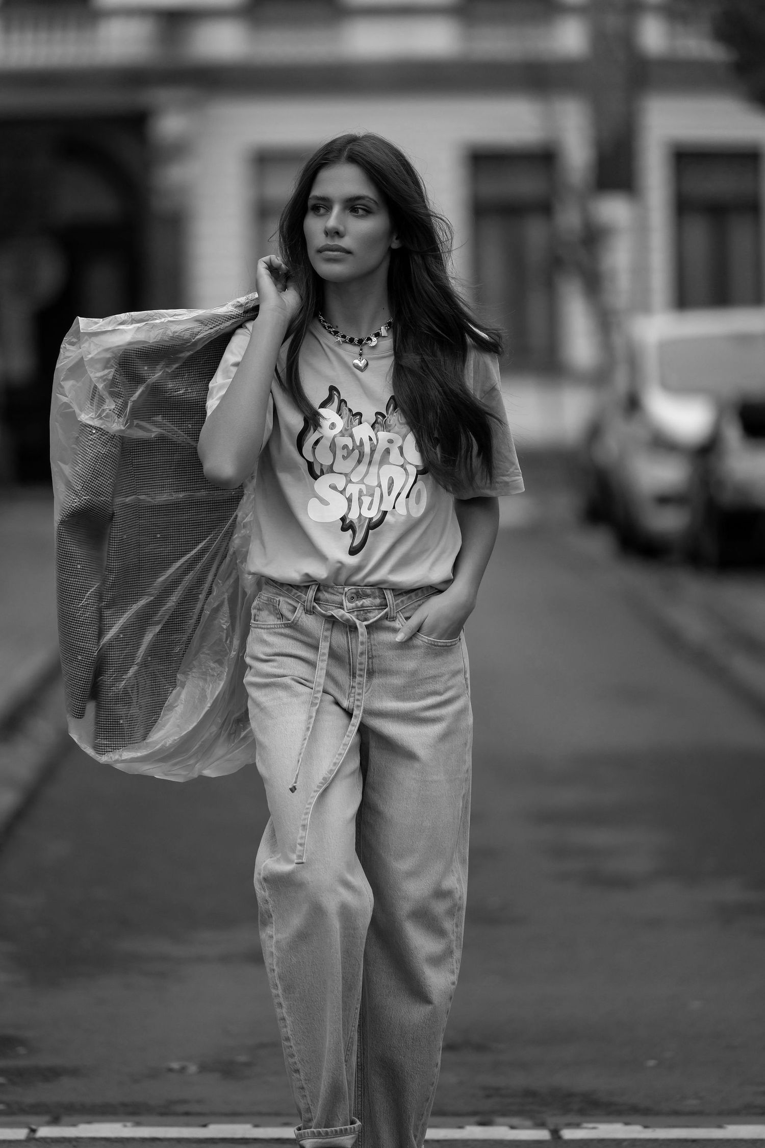 Black and white street photography of someone carrying shopping bags while wearing casual denim.