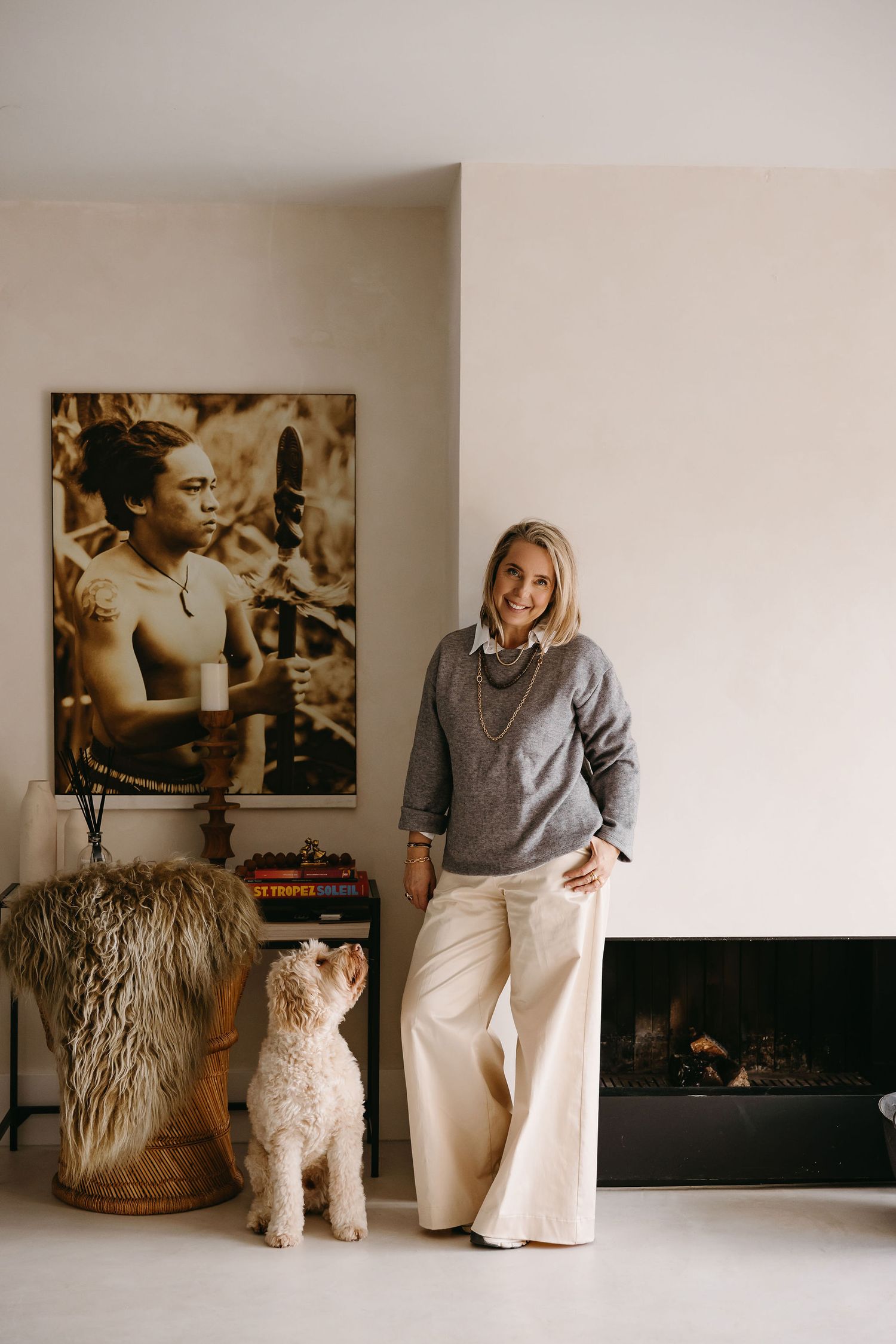 Modern home interior with white walls, vintage artwork, and fluffy white dog near fireplace.