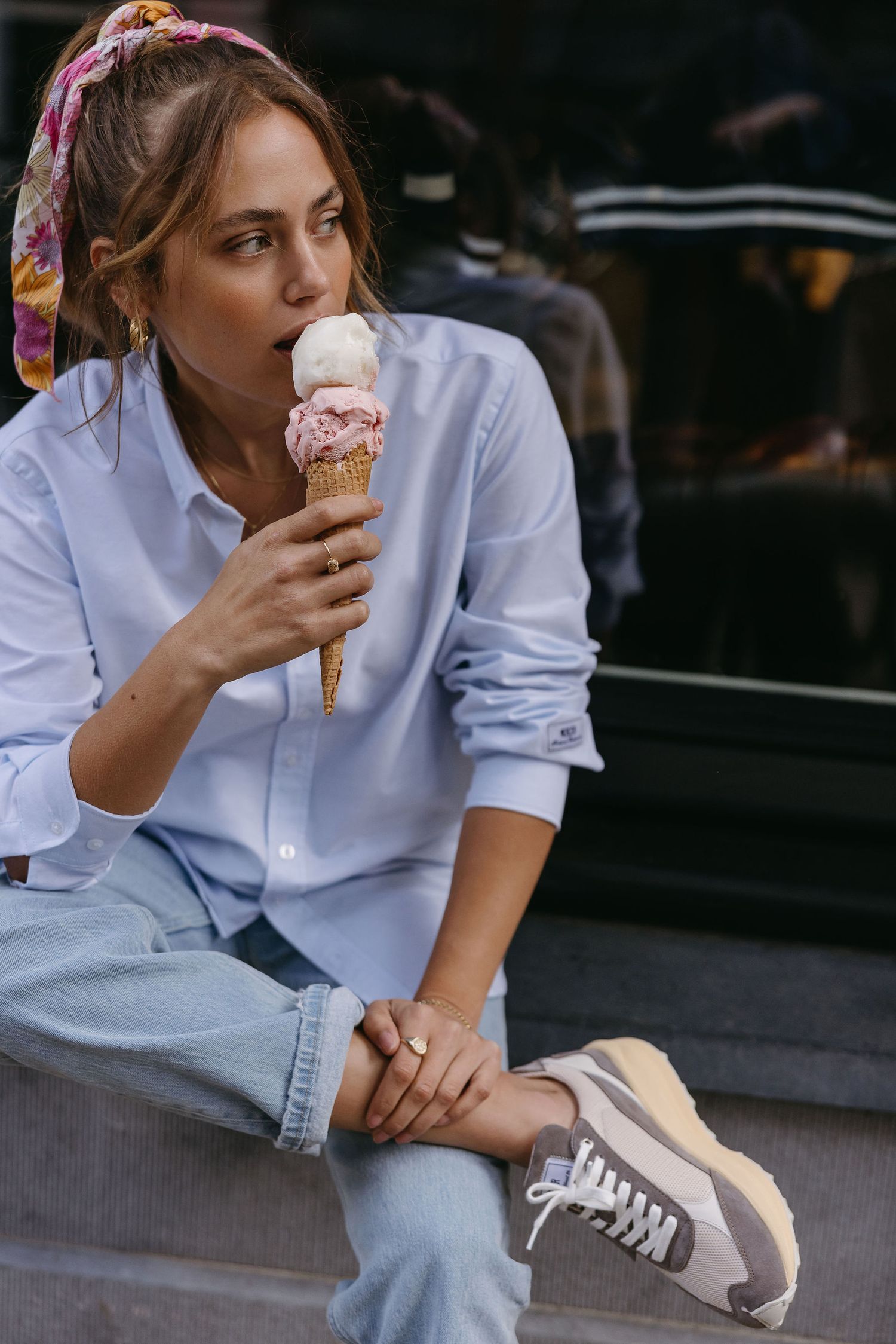 Person in casual summer outfit enjoying ice cream cone while sitting outdoors.