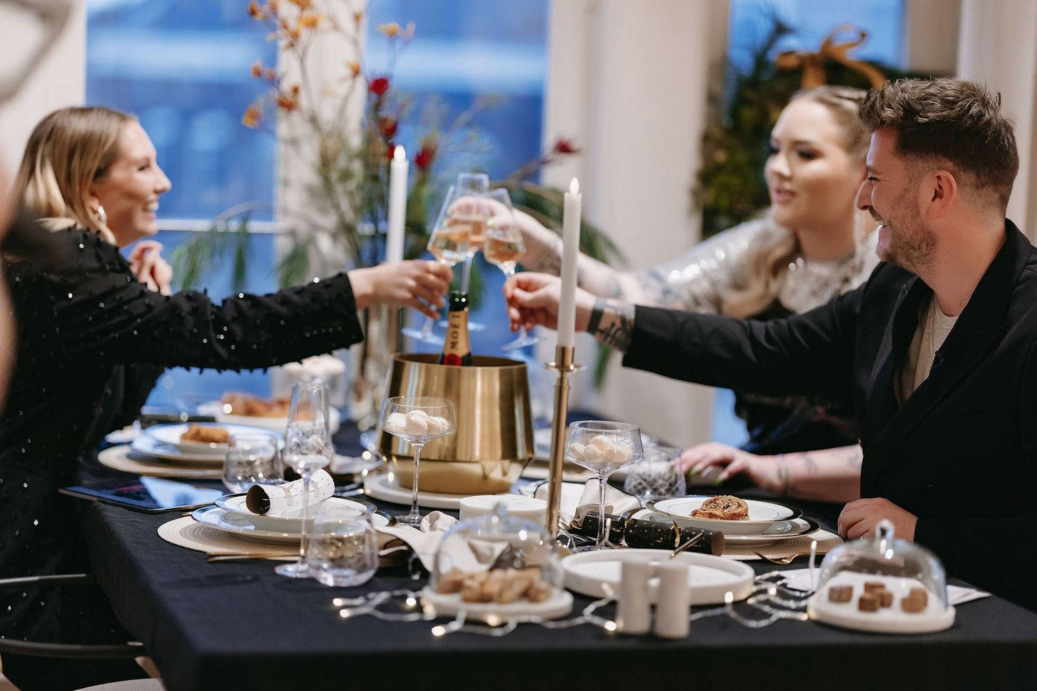 People toast and celebrate at an elegantly set dining table with decorative centerpieces.