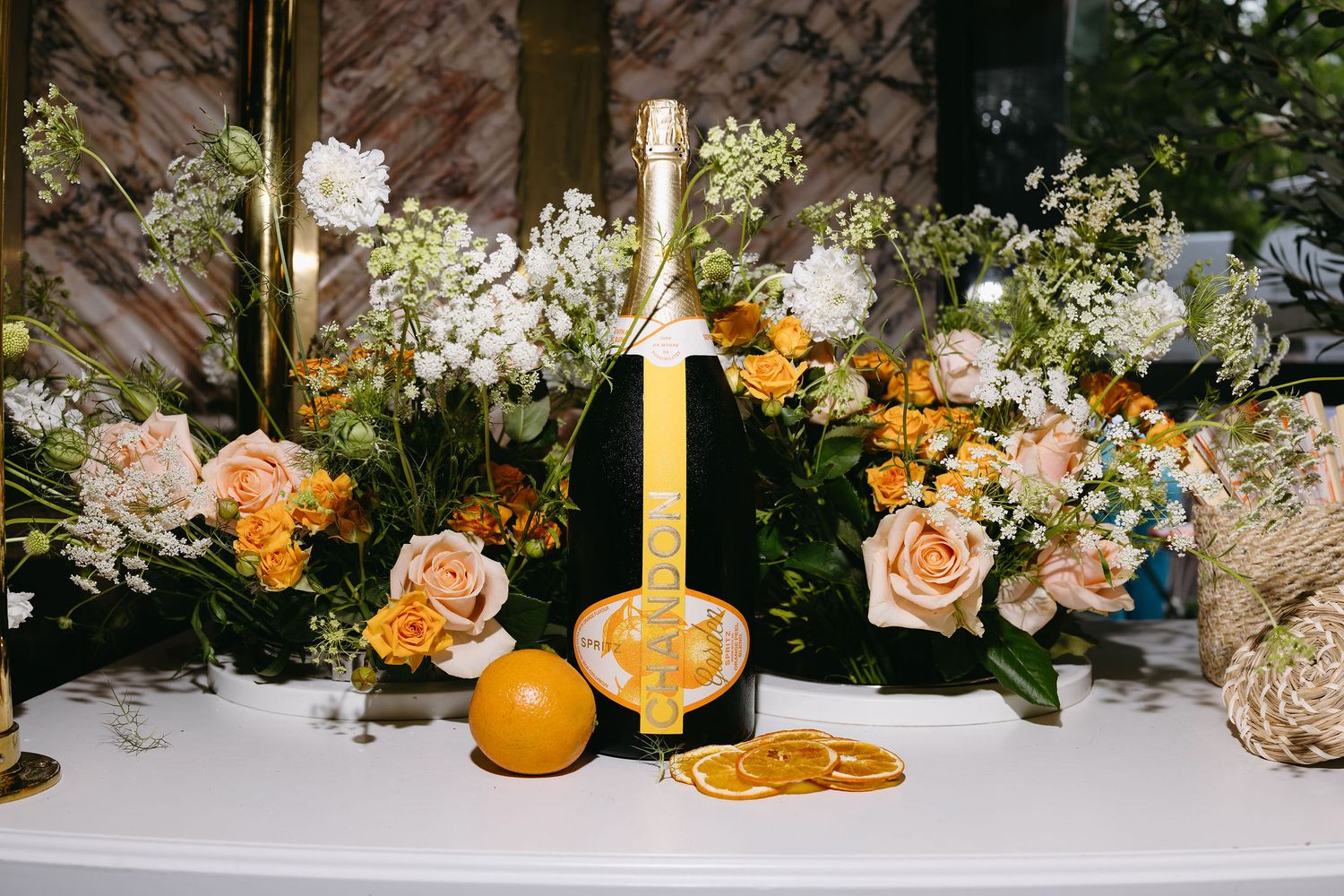 Champagne bottles and floral centerpieces with orange accents on elegant table display.
