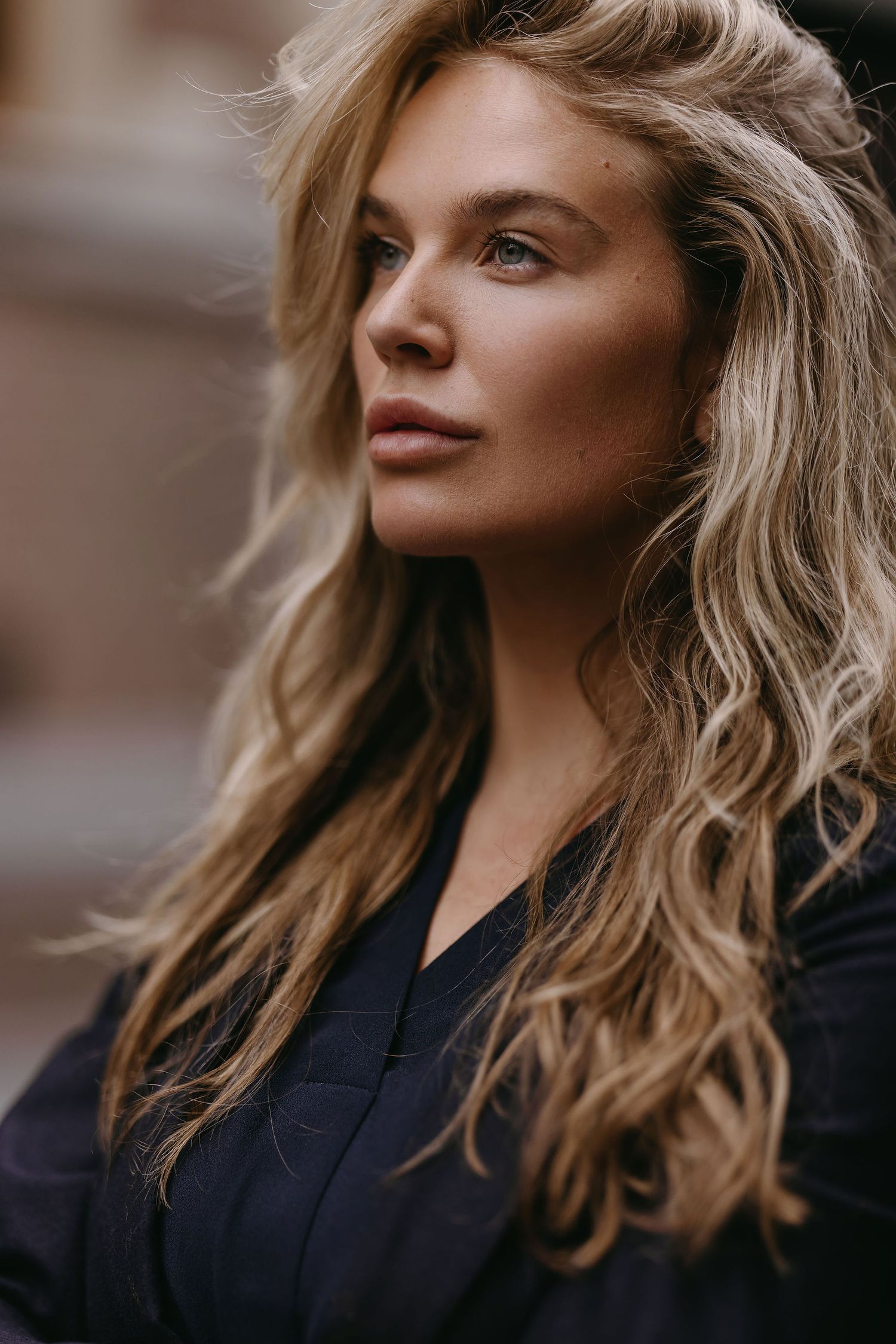 Professional fashion portrait of a blonde woman in a black top with natural lighting and soft focus.
