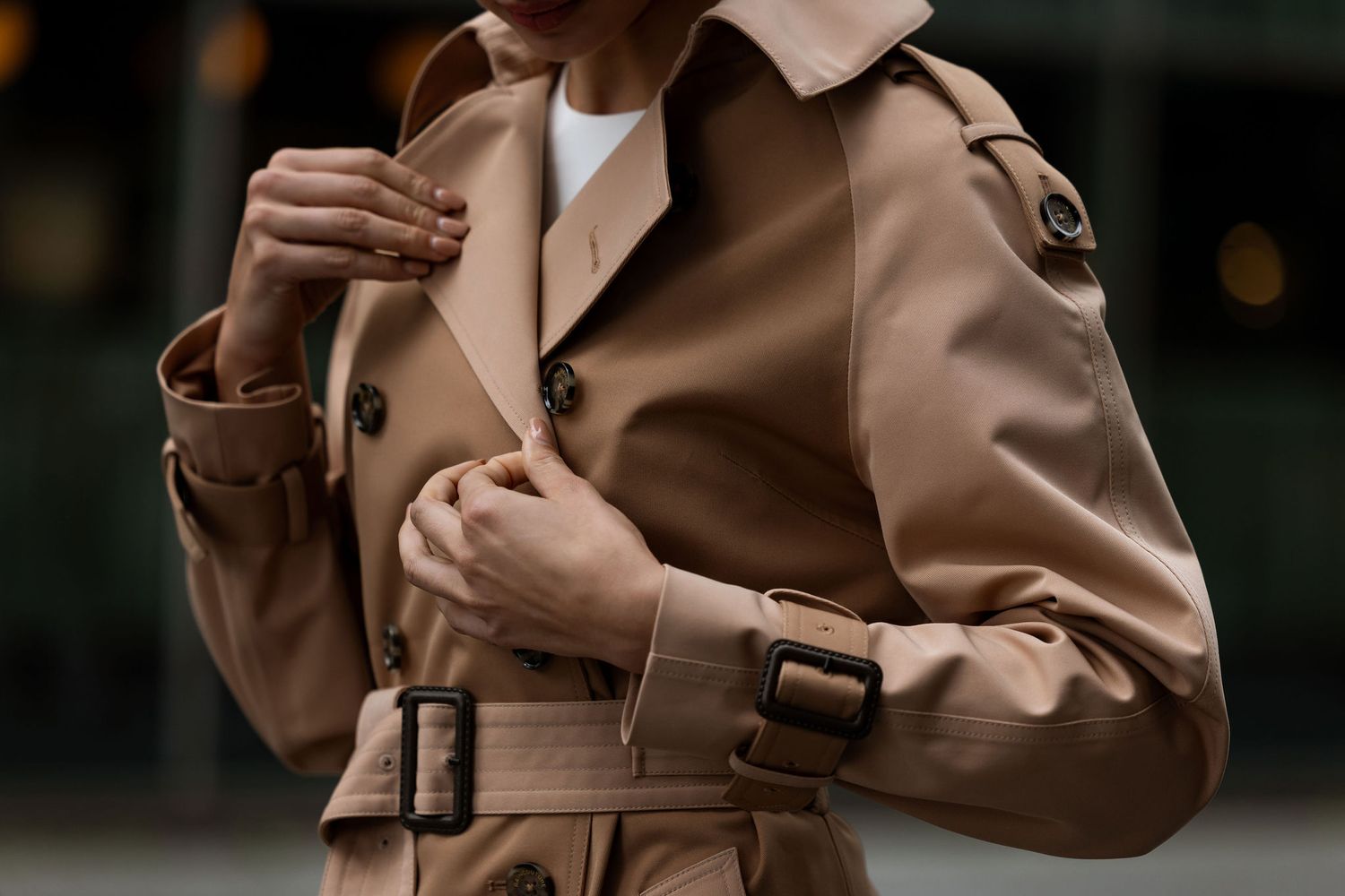 Close-up detail of camel trench coat with belt and buckle details.