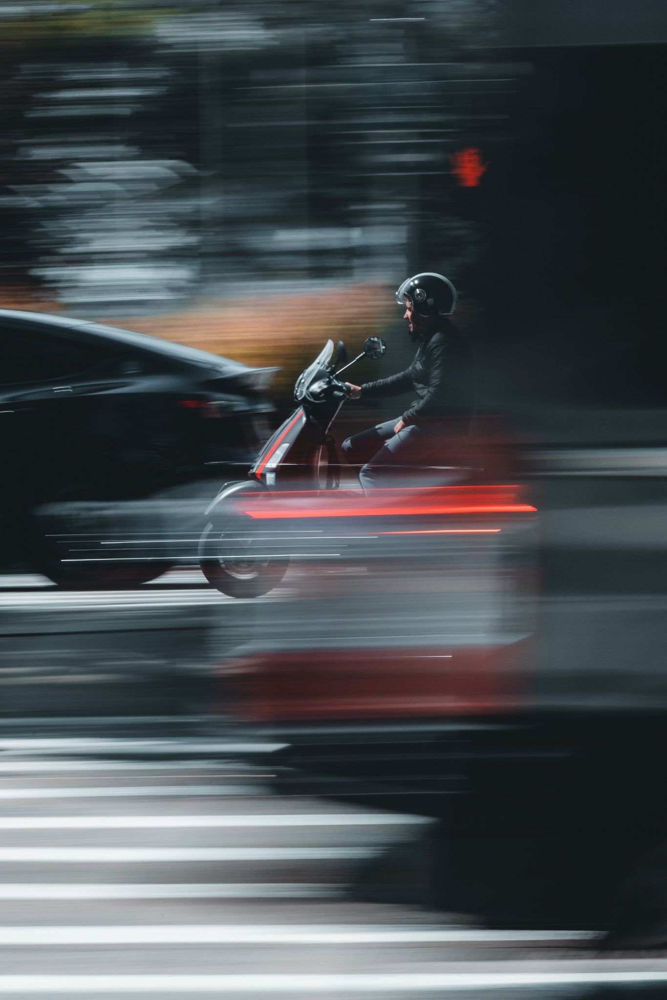 A motorcyclist in a black helmet rides through a city street at night, captured with motion blur effect.