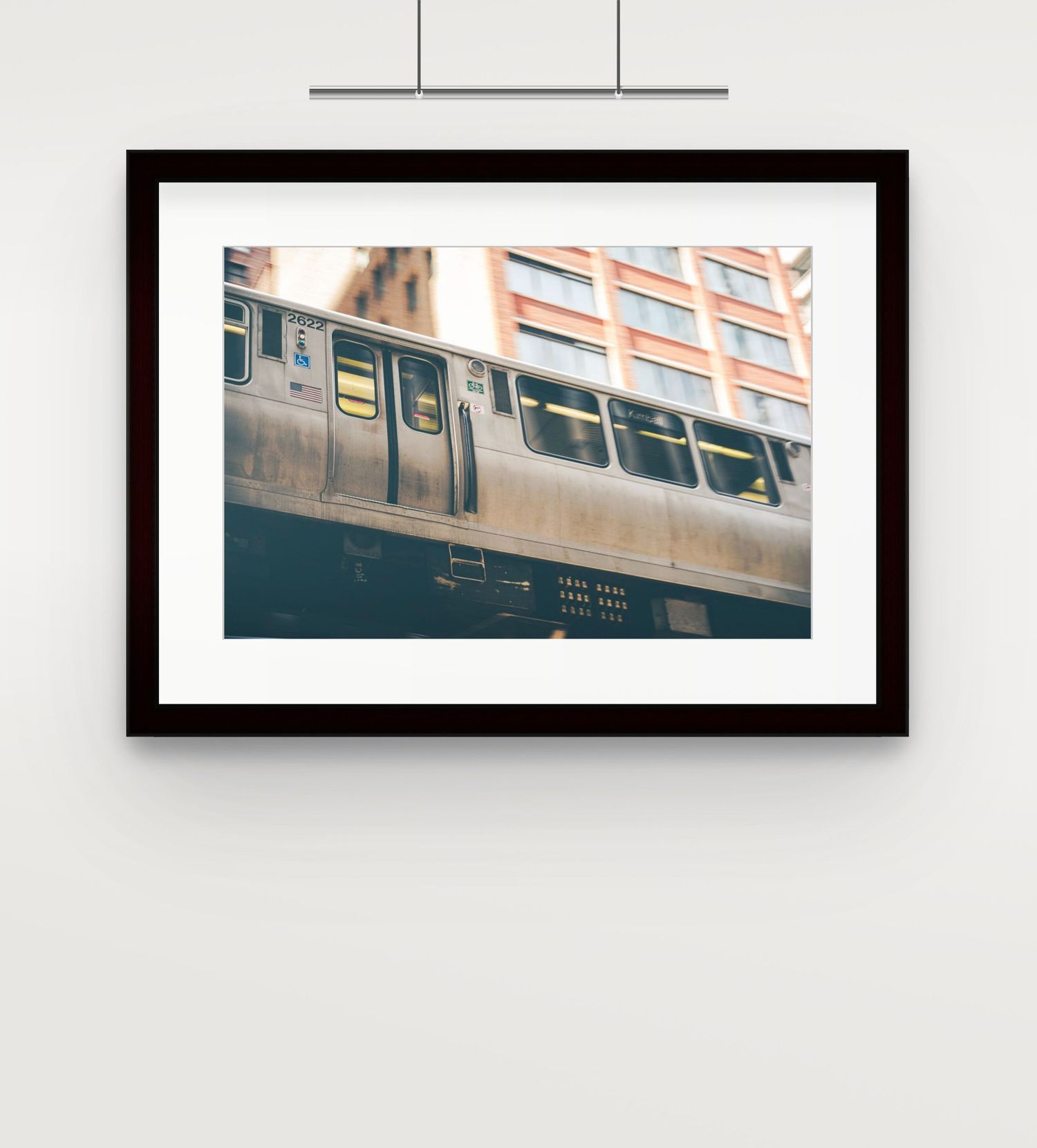 Framed photo of Chicago elevated train passing urban brick building on wall.