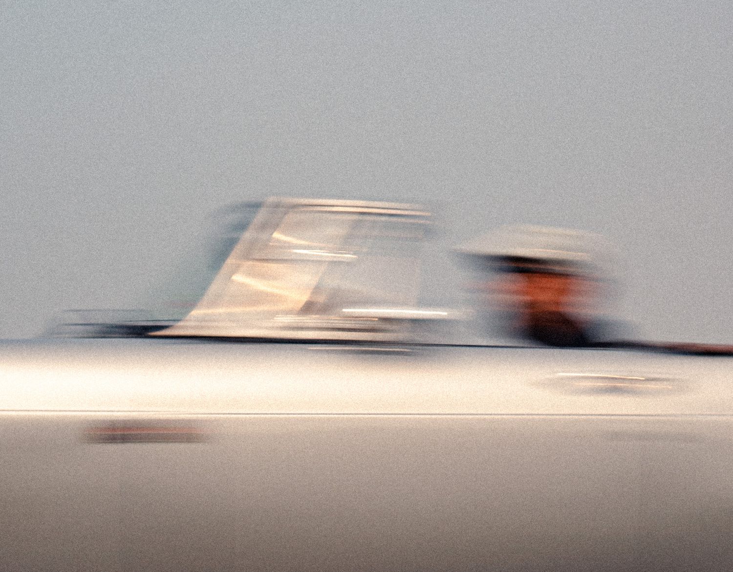 A motion-blurred speedboat races across calm water with a person visible at the helm.