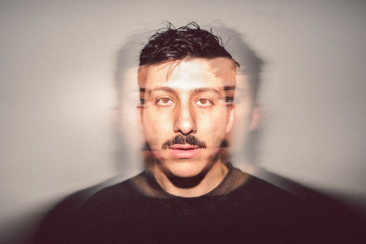 Double exposure close-up portrait of young man with mustache on gray background.