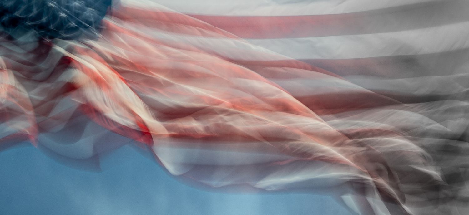An American flag waving in the wind, captured with a dreamy motion blur effect.